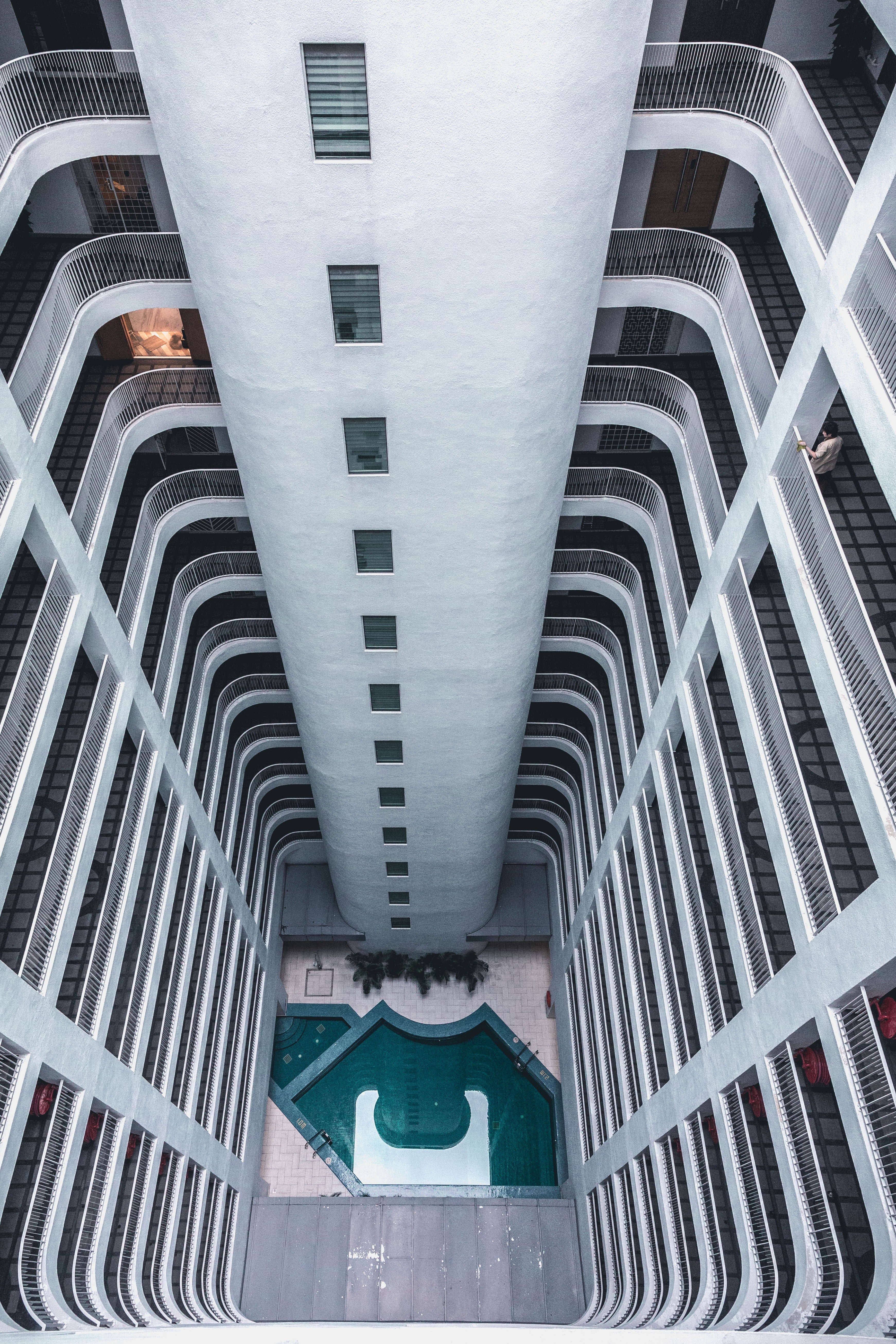 looking down from the top of a tall apartment building with many windows onto pool below, international plaza 4k, Phone HD Wallpaper