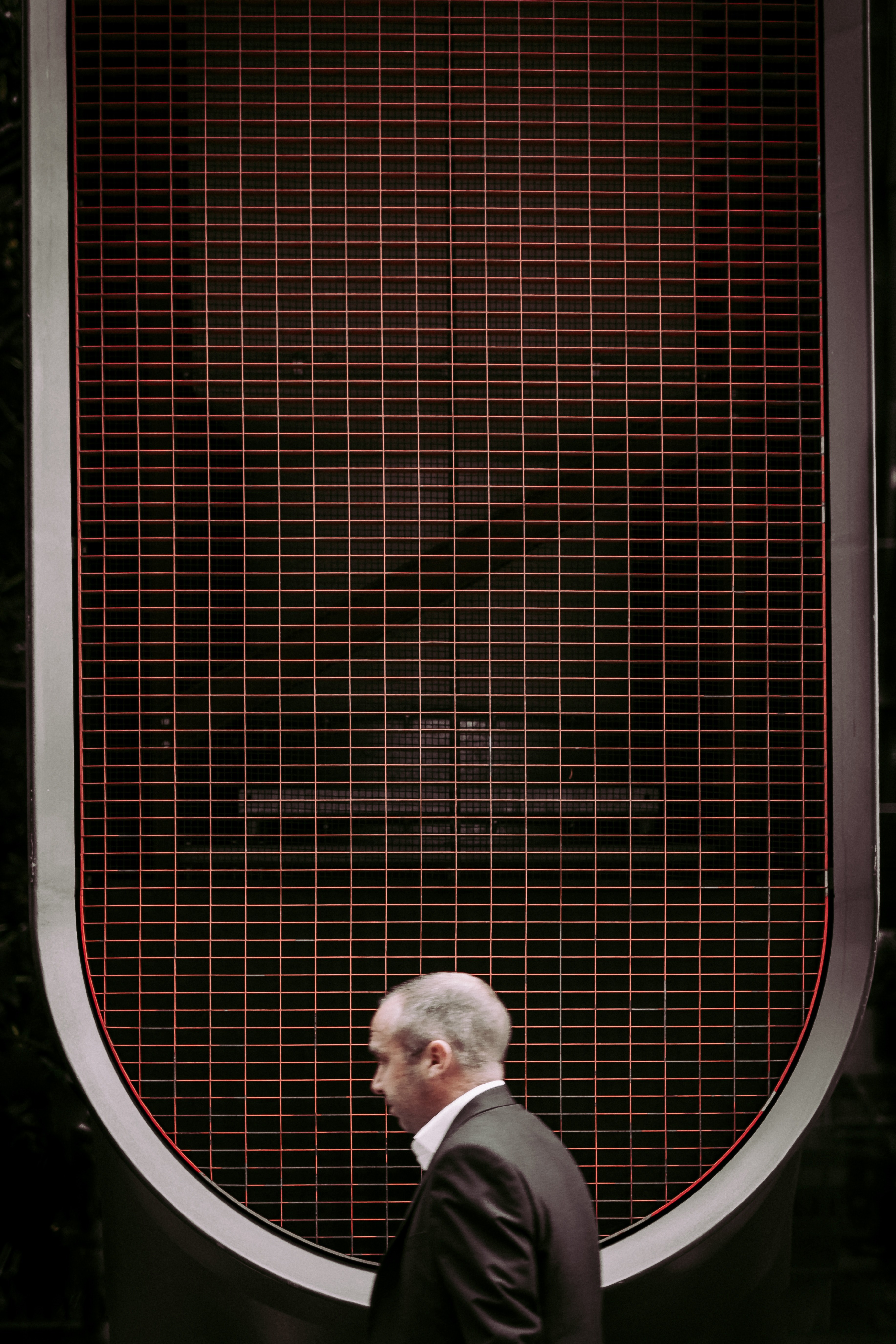 a low angle shot of a man in a black suit under a grid on the roof, man in city 4k, Phone HD Wallpaper