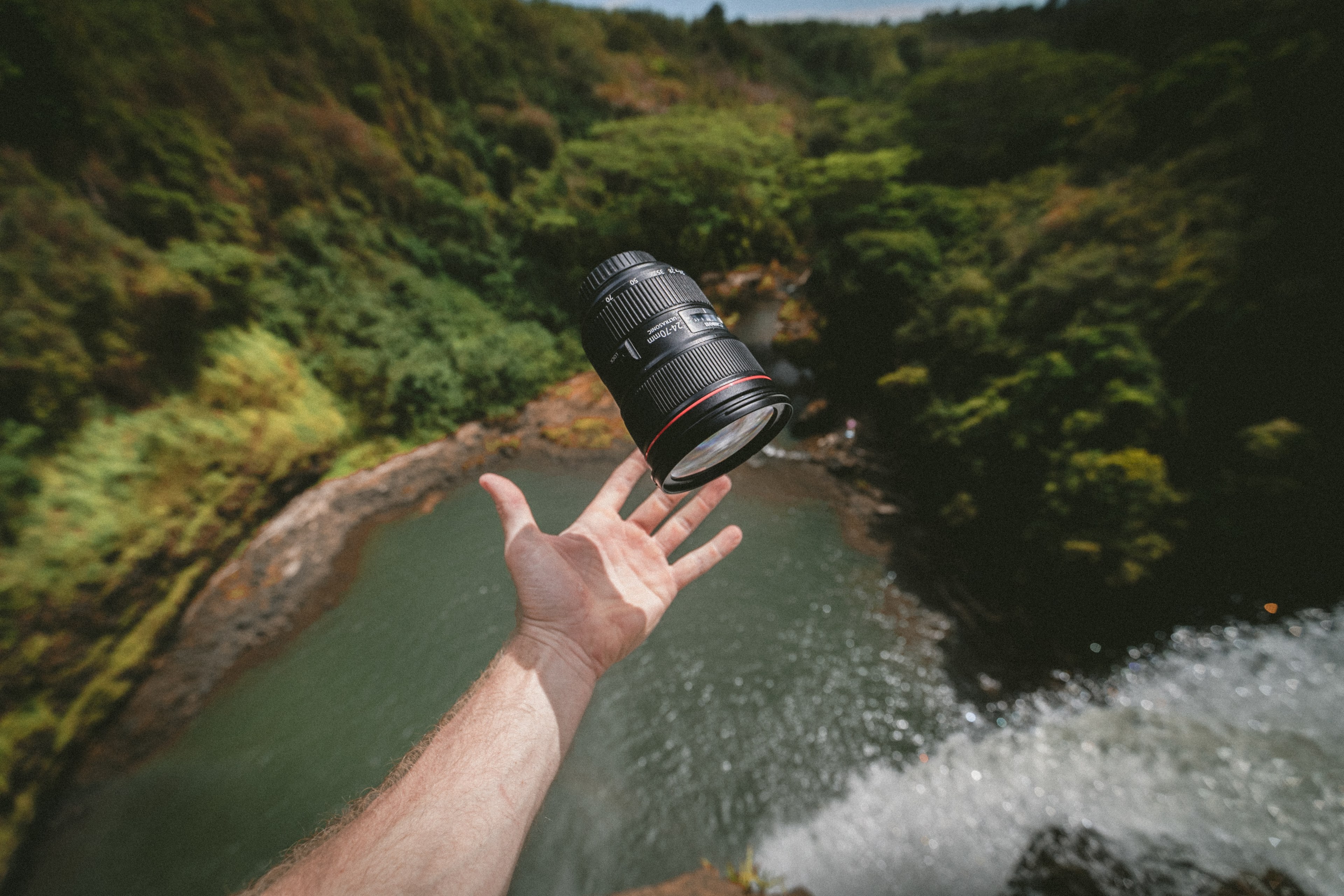 a man throwing a zoom lens up in the air over a tall waterfall, floating canon lens 4k, HD Wallpaper
