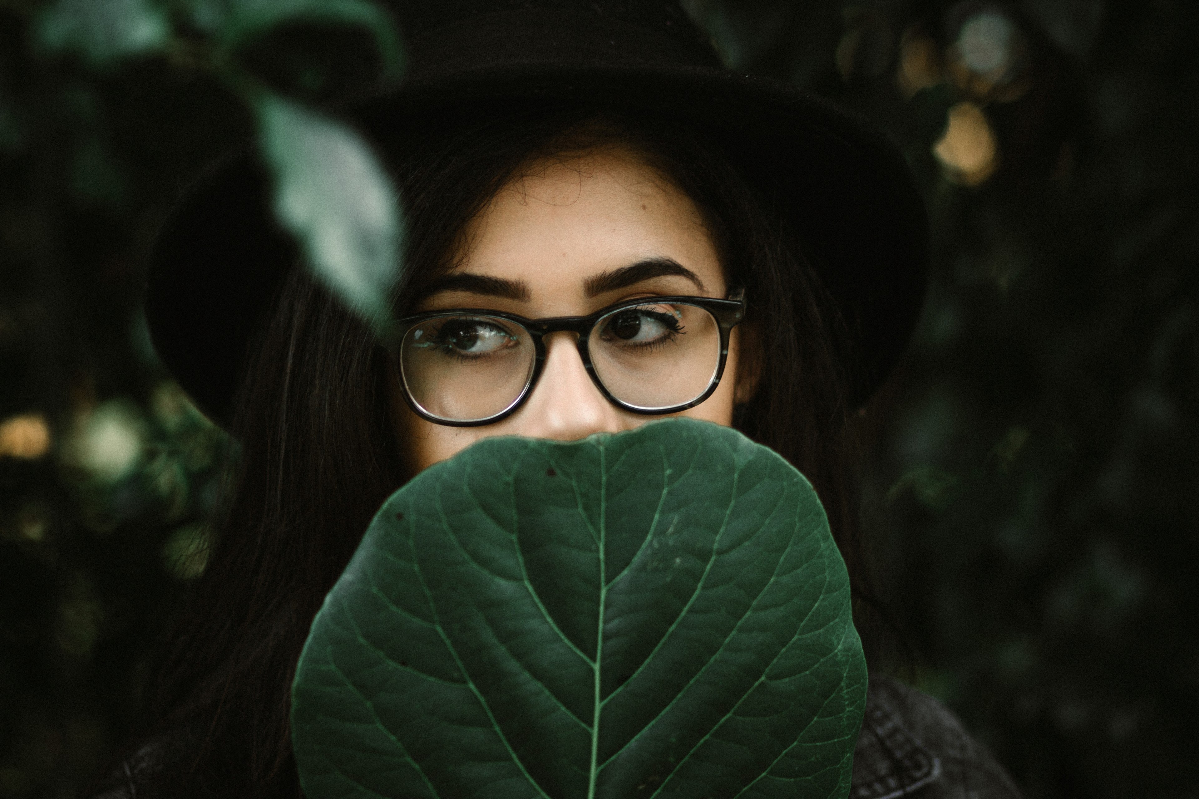 woman with bold eyebrows and thick rimmed glasses behind a leaf, so take a deep breath and let it go 4k, HD Wallpaper