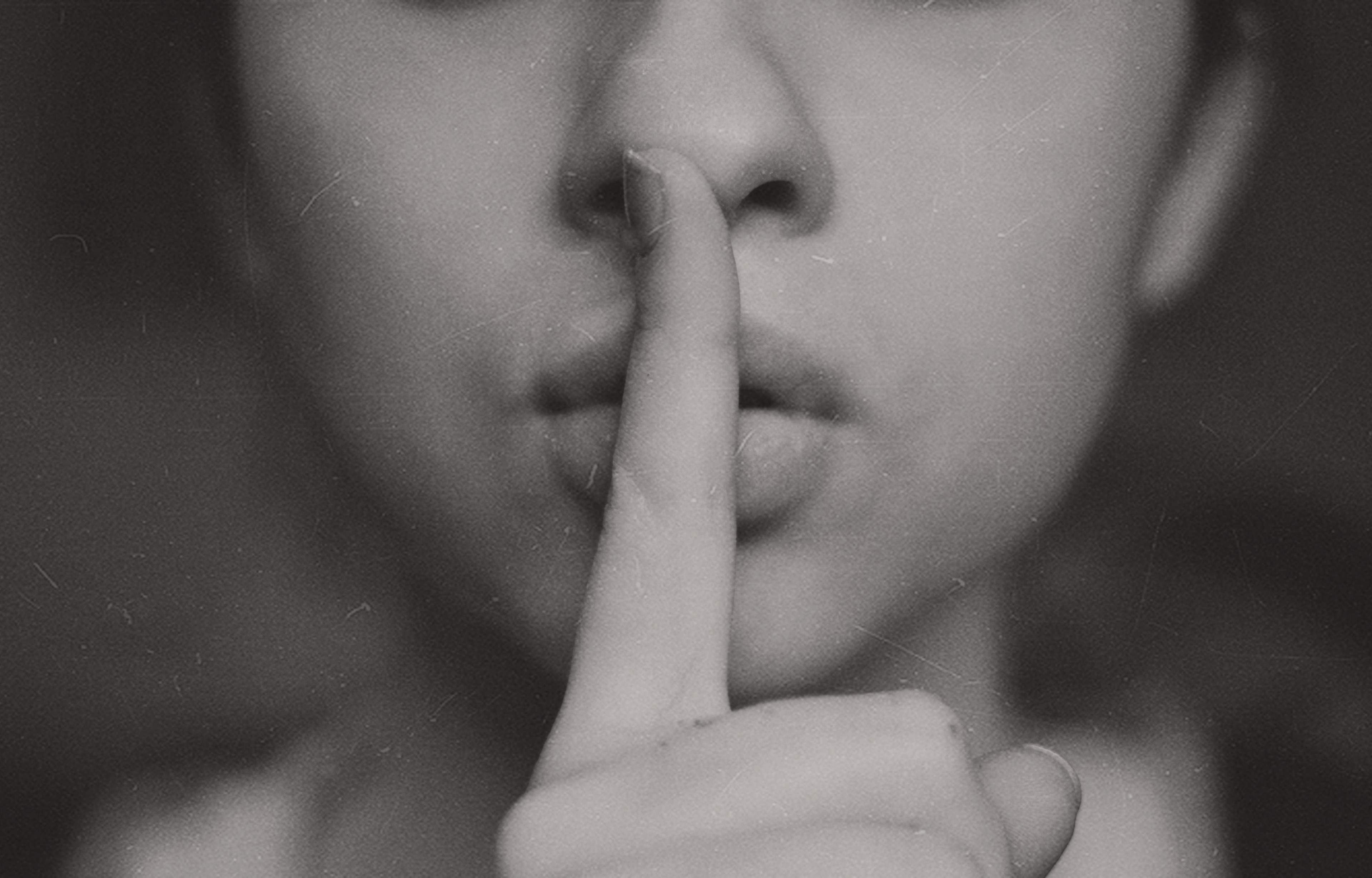a black and white shot of a woman putting a finger over her lips in a gesture of silence, secret 4k, HD Wallpaper
