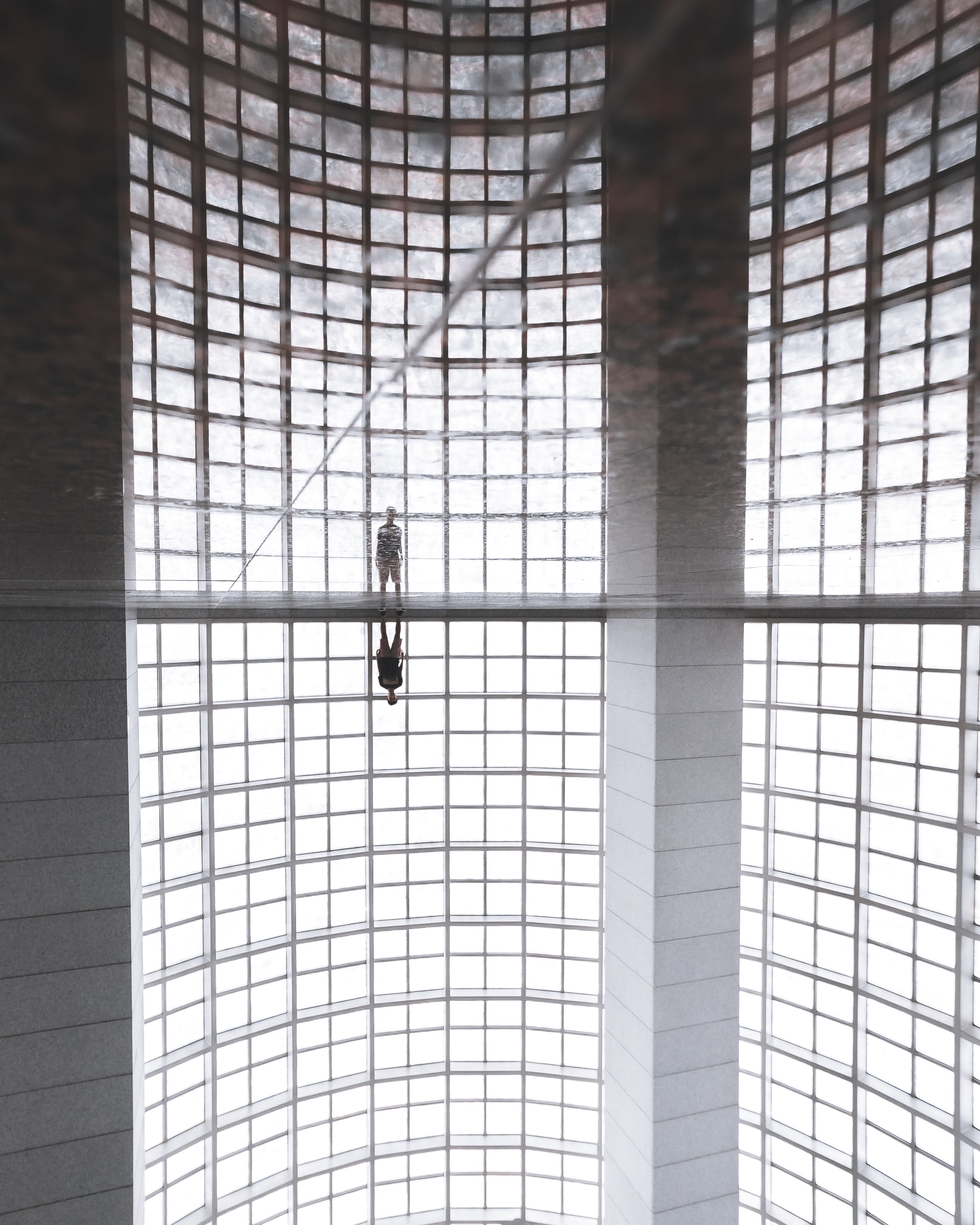 a distant shot of a person standing near the wall of a building with a reflective floor, lone person and reflection 4k, Phone HD Wallpaper