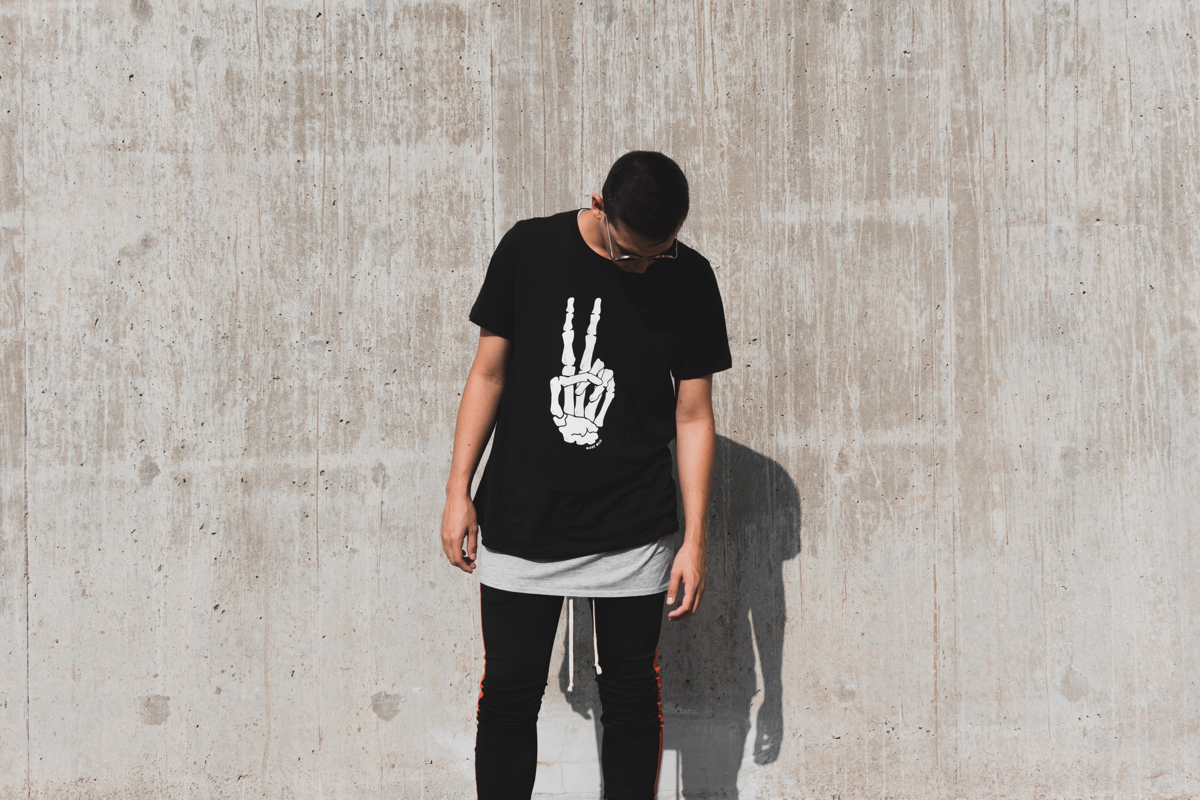 a person standing by a wall wears a t shirt with a skeleton hand making a peace sign, peace yo 4k, HD Wallpaper