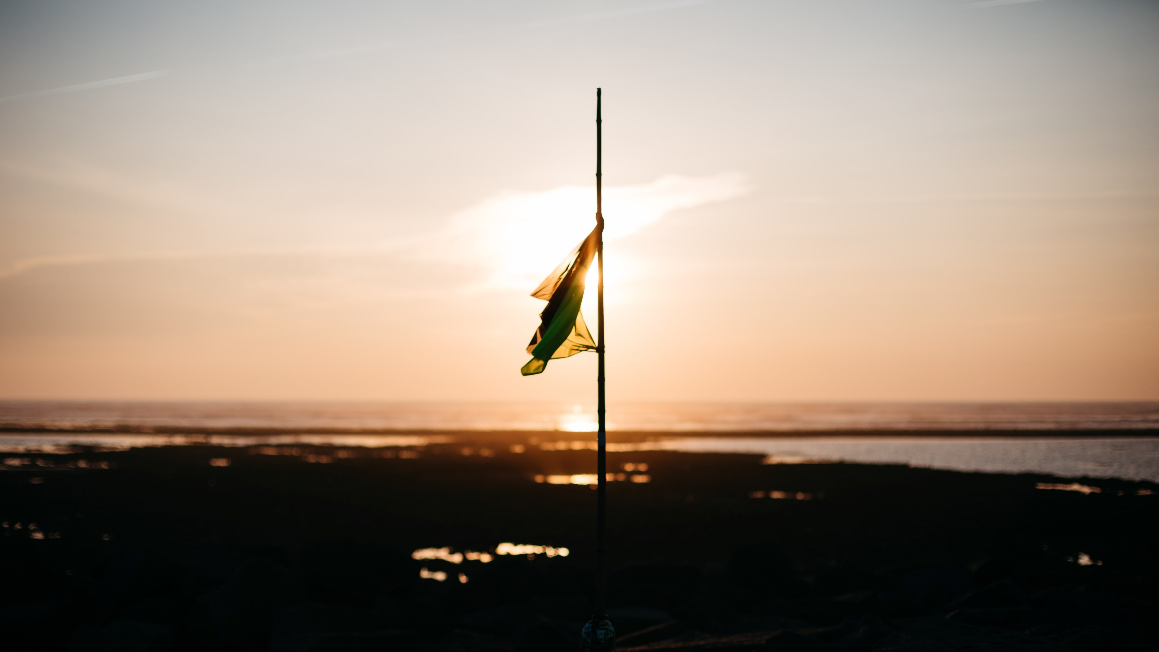 a flag at half mast on a flat shoreline with the sun setting behind it in ars en r, _lost flag 4k, HD Wallpaper