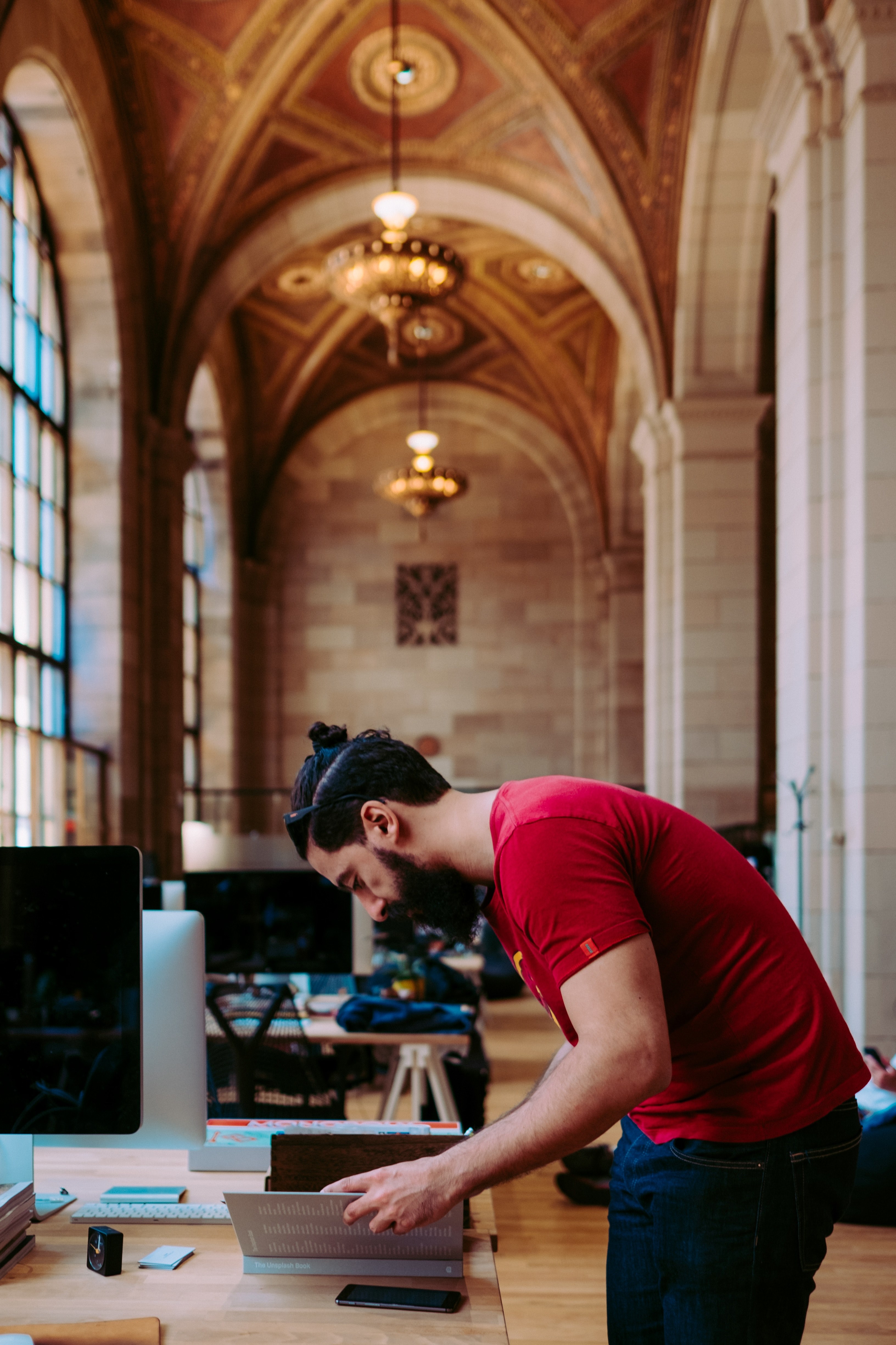a bearded man leaning over a book on a table in a vast office space, unsplash hq crew collective amp cafe montreal 4k, Phone HD Wallpaper