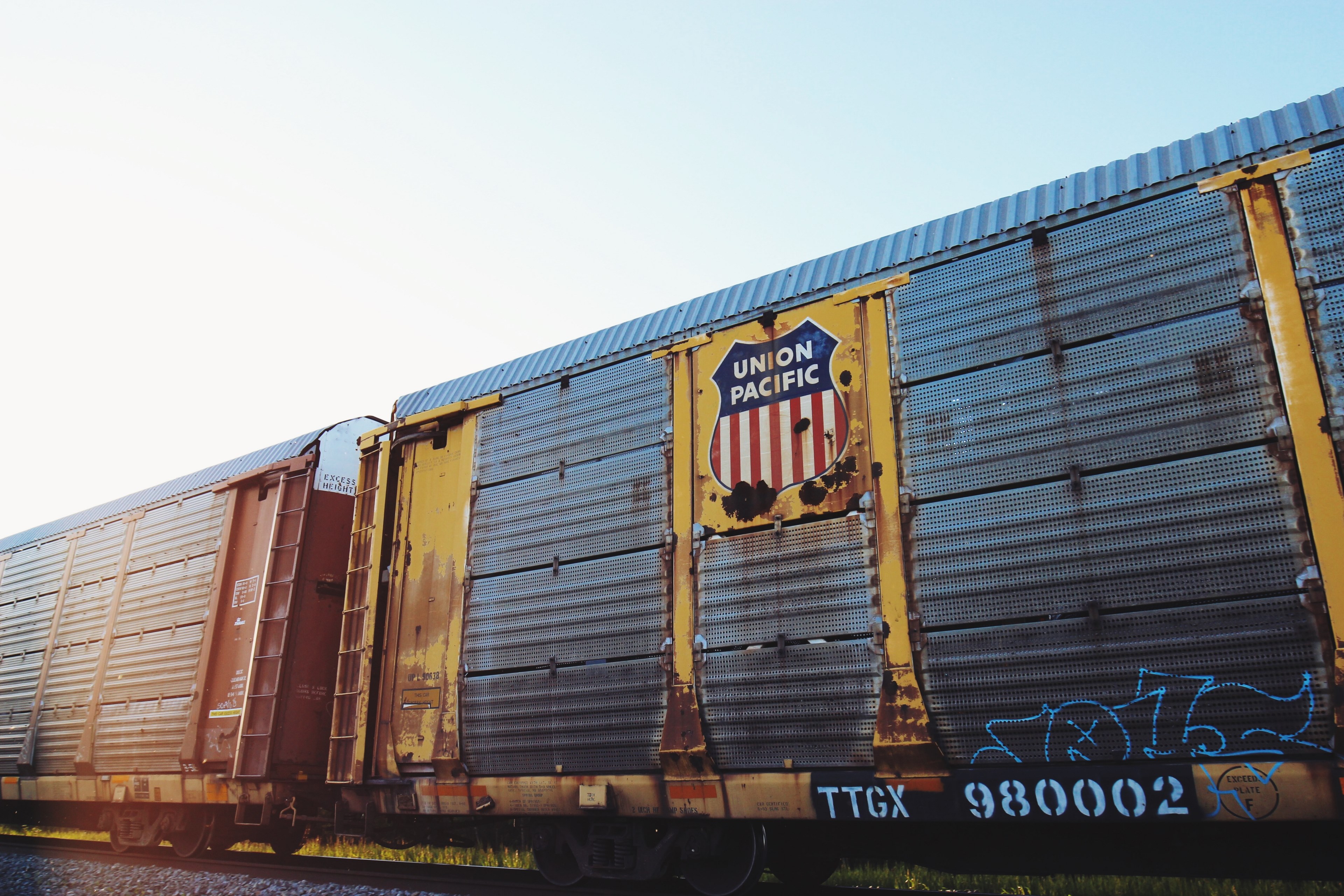 an old rusting union pacific railcar with blue graffiti on it passing a grassy area under a clear sky, union pacific freight car 4k, HD Wallpaper
