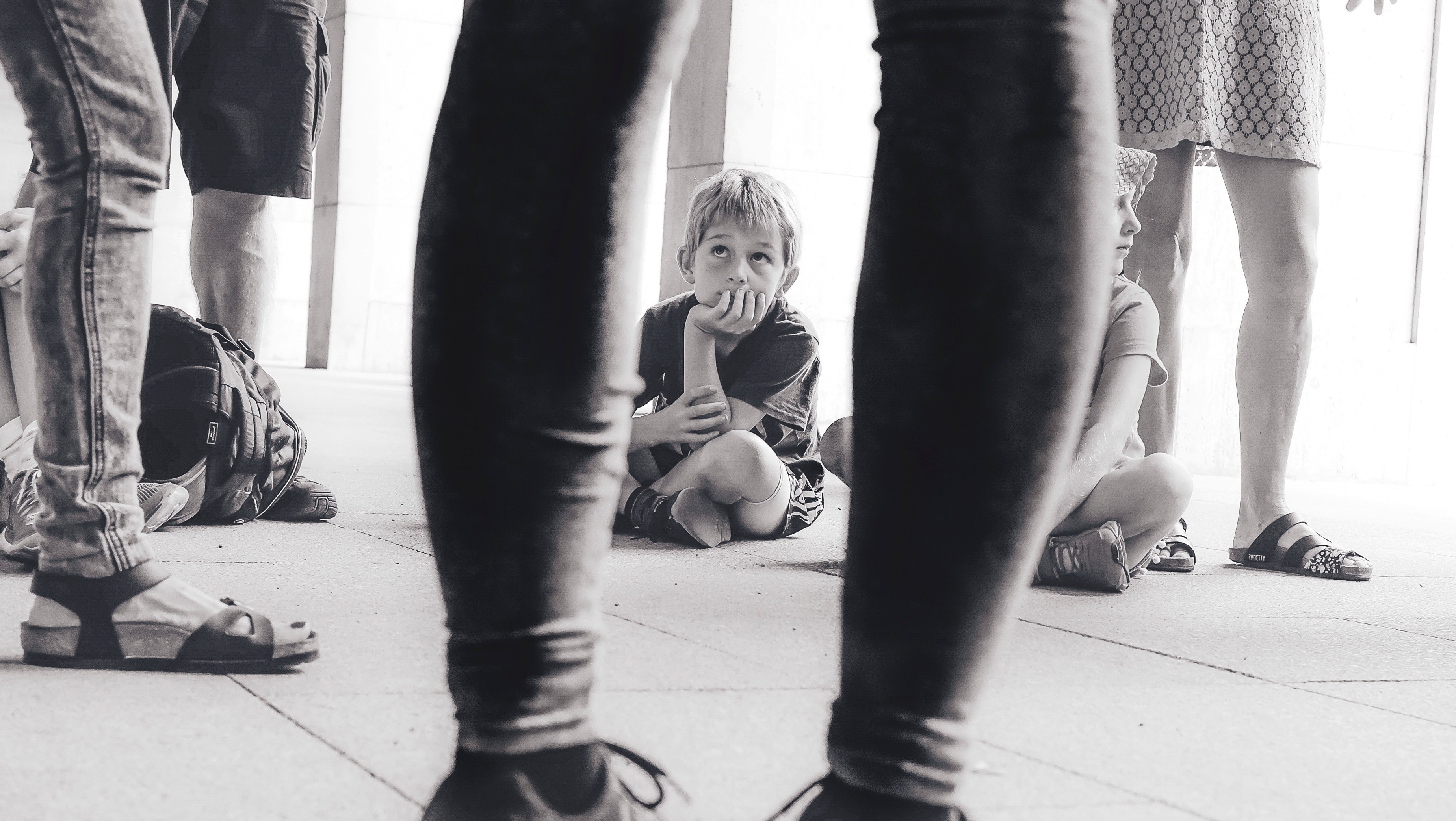 black and white through persons legs shot of child sitting in berlin, berlin child through legs 4k, HD Wallpaper