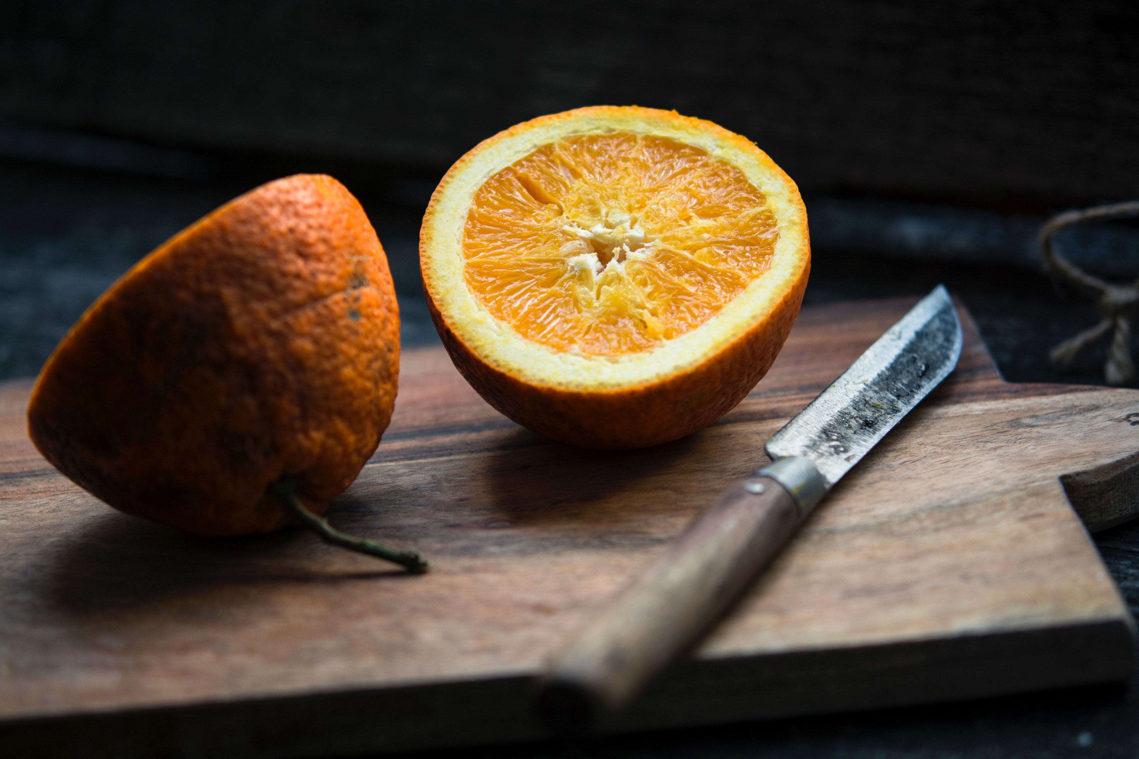 fresh orange slice in half on a rustic cutting board, preparing a healthy snack 4k, HD Wallpaper