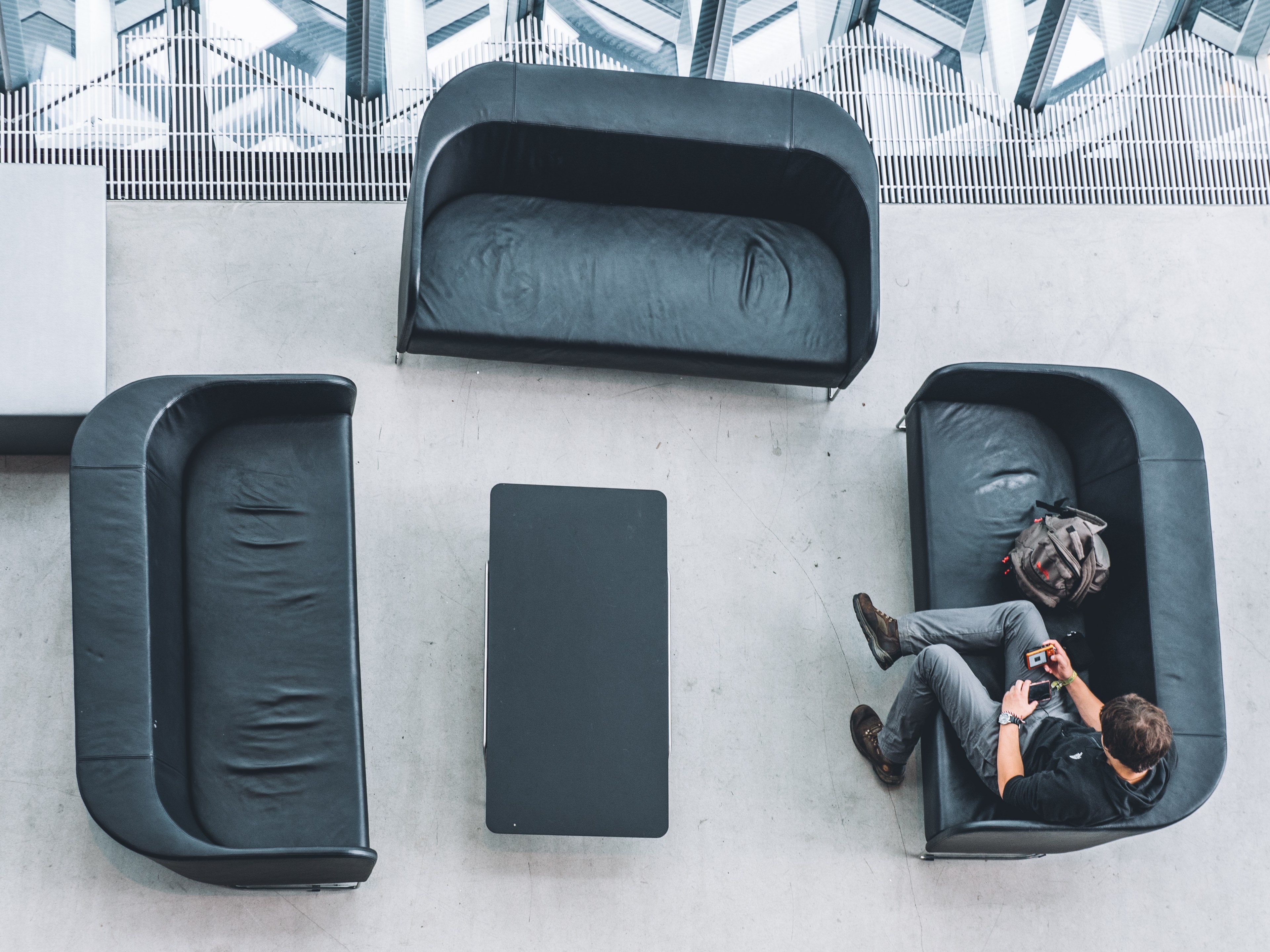 drone view of three black couches surrounding a black coffee table with man sitting, three black couches drone view 4k, HD Wallpaper