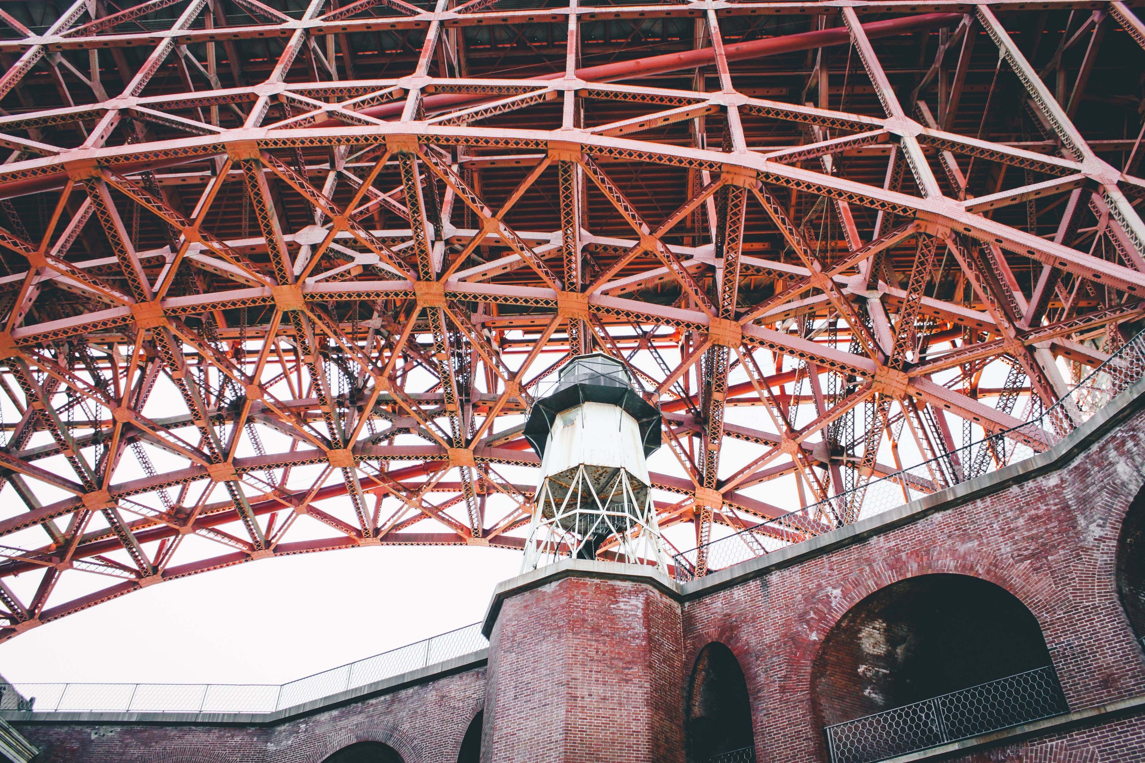 a white tower and brick walls under a large bridge like steel structure, under massive steel structure 4k, HD Wallpaper
