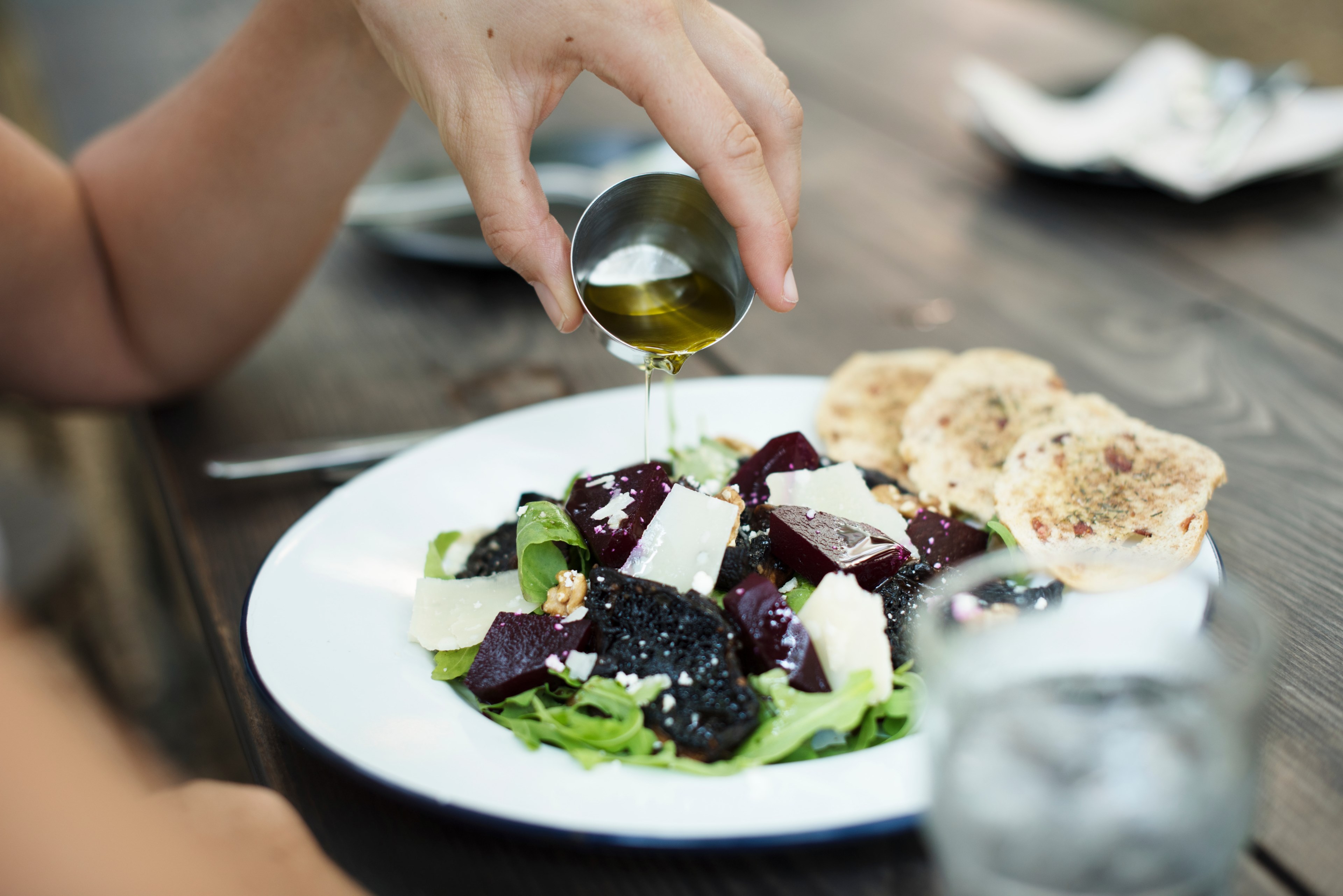 a person a small container of oil over a salad with croutons on a wooden table, pouring oil over salad 4k, HD Wallpaper