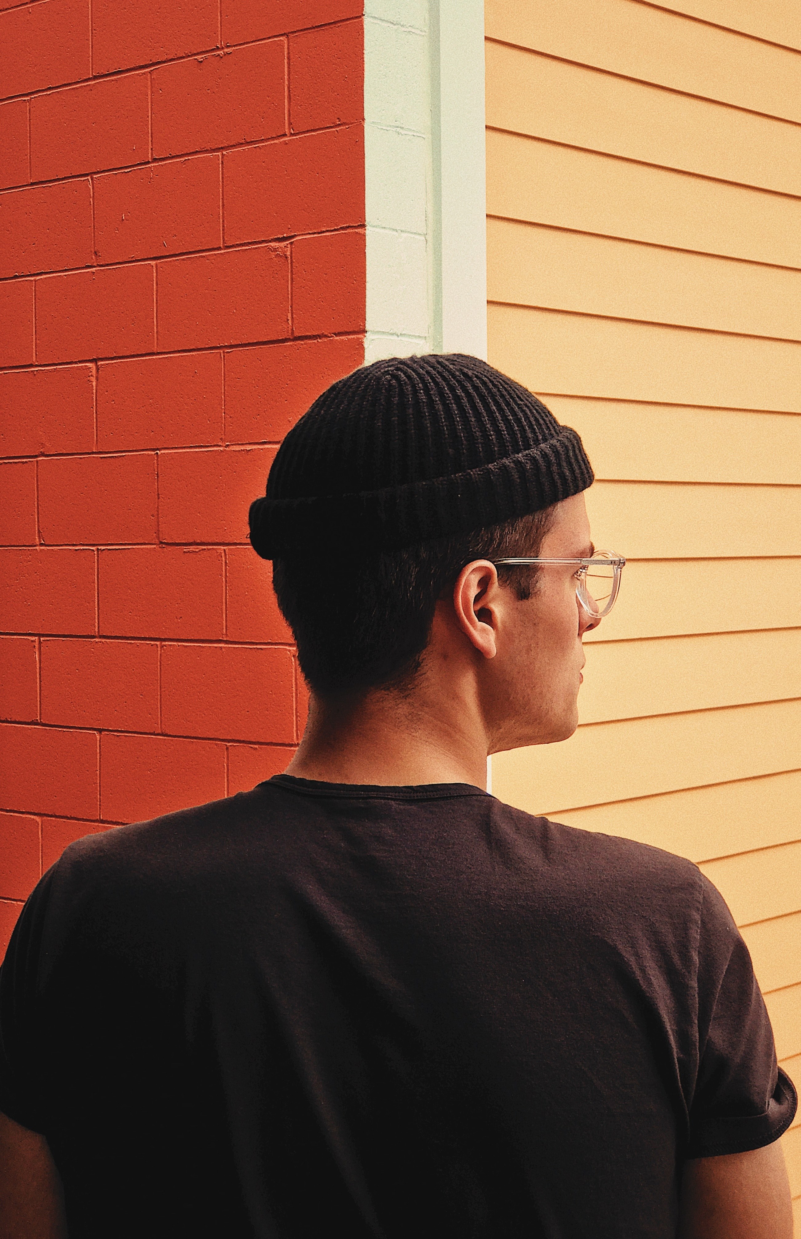 a mixed race mal wearing glasses looking to the right while standing in front of a building corner, _art 4k, Phone HD Wallpaper