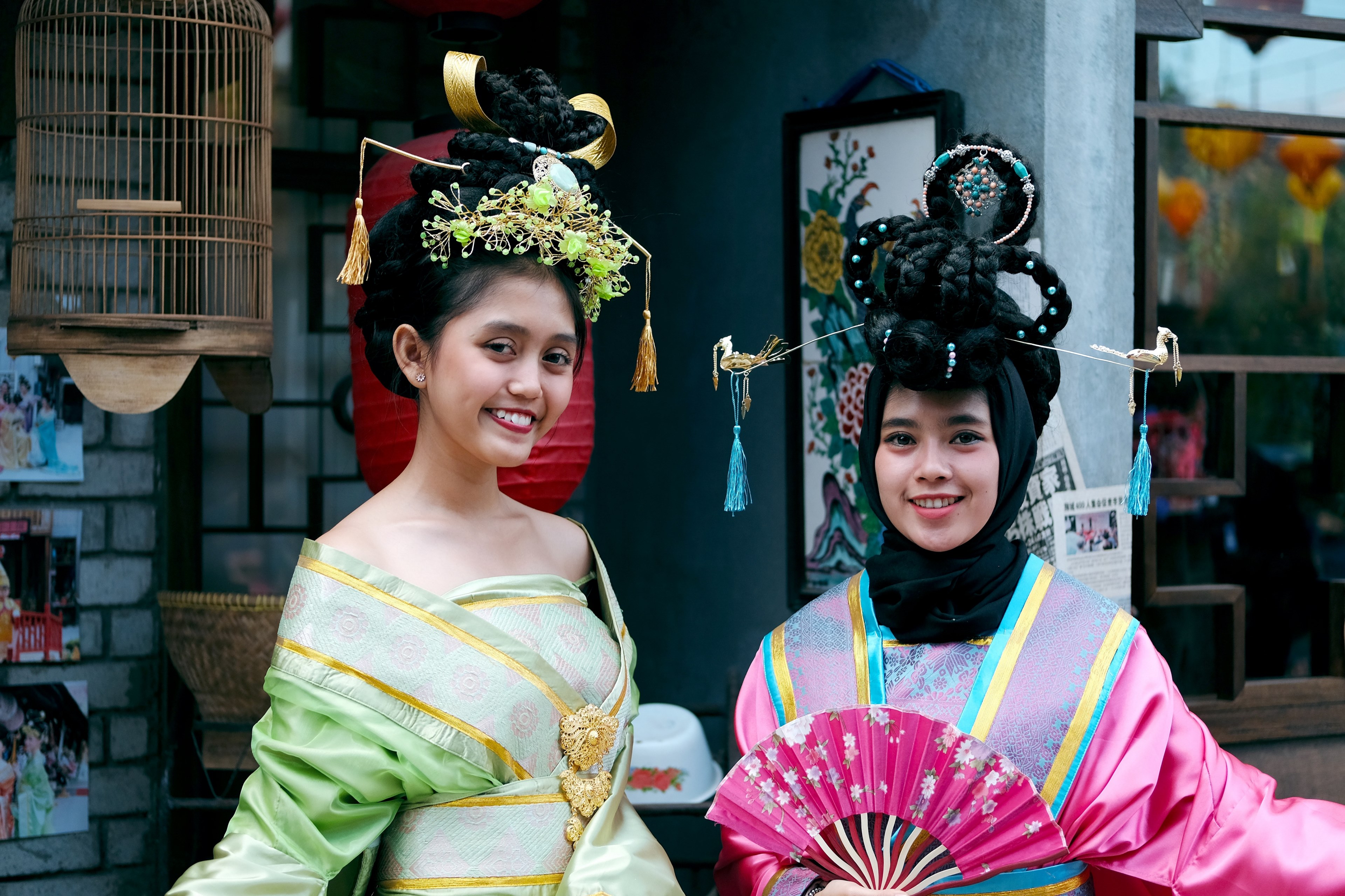 two smiling women in intricate headdresses and traditional clothing with a fan outdoors in bandung, chinese women smile 4k, HD Wallpaper