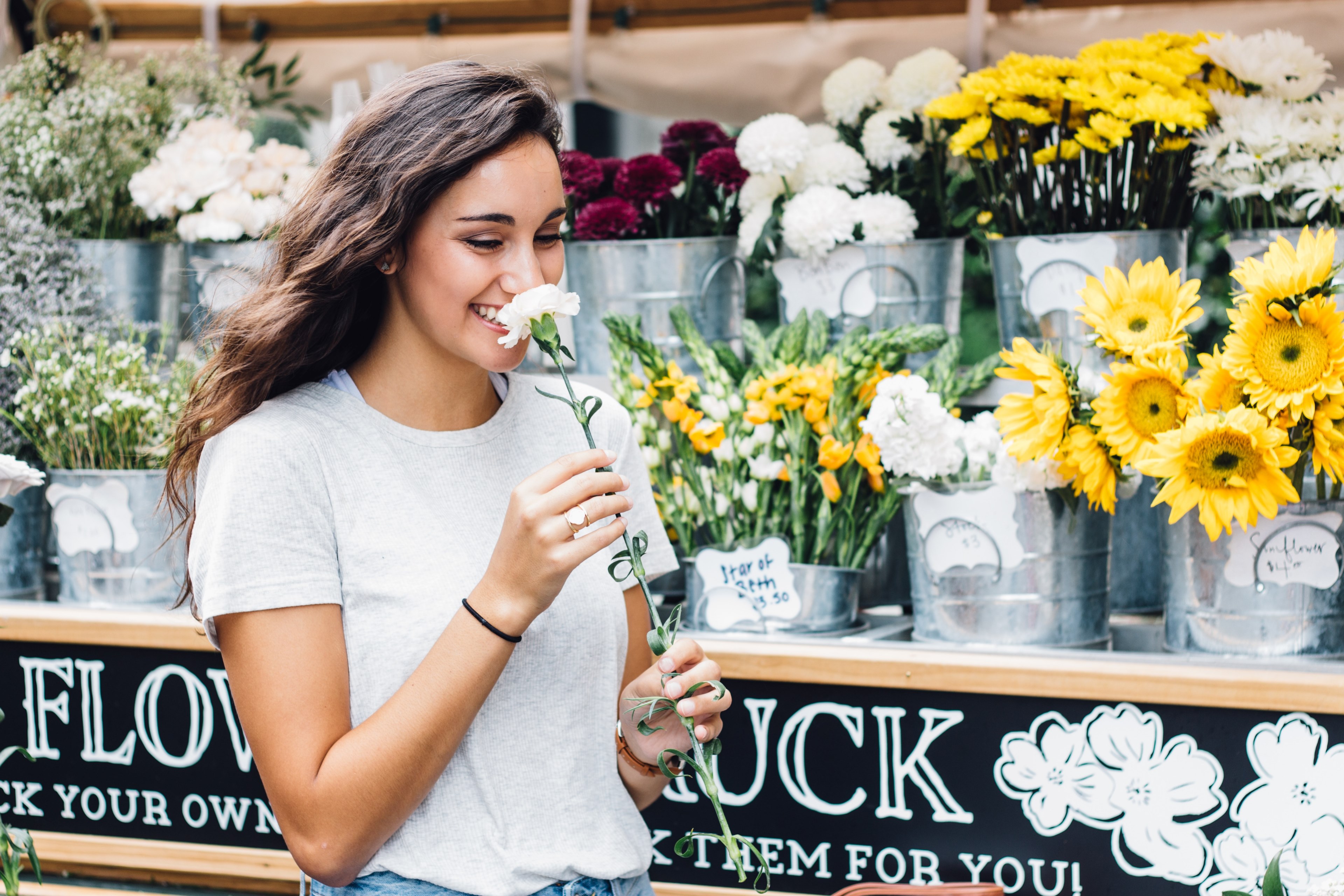 a woman at a floral stand in nashville smiles while smelling a white flower, woman smelling a flower 4k, HD Wallpaper