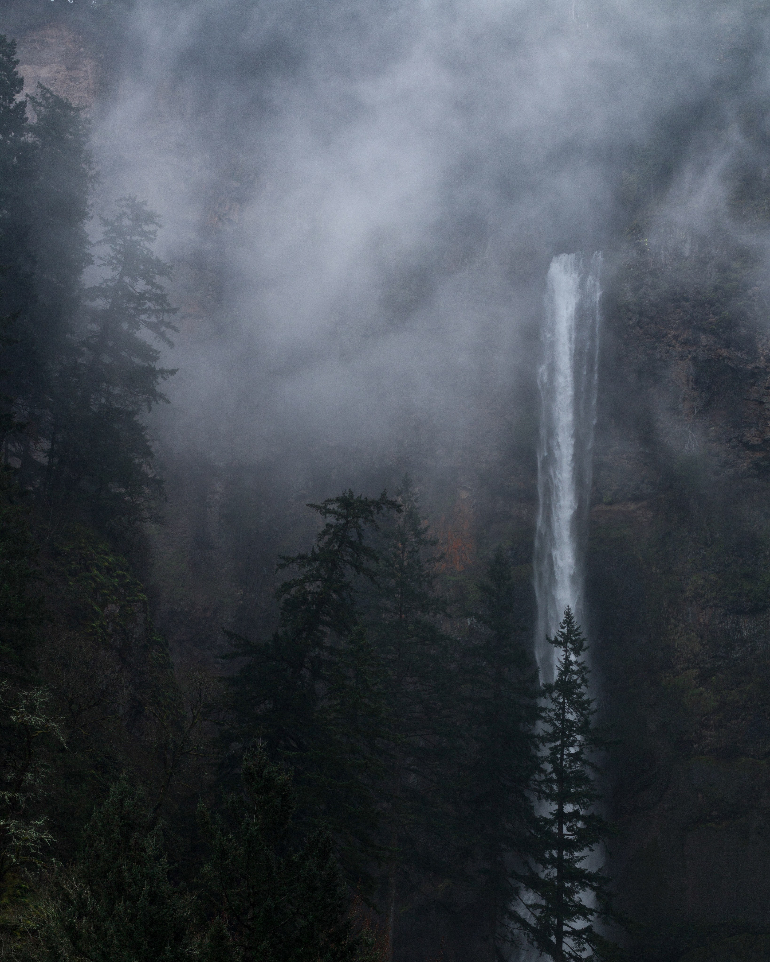 a tall waterfall on a mist wreathed rock face, waterfall behind mist 4k, Phone HD Wallpaper