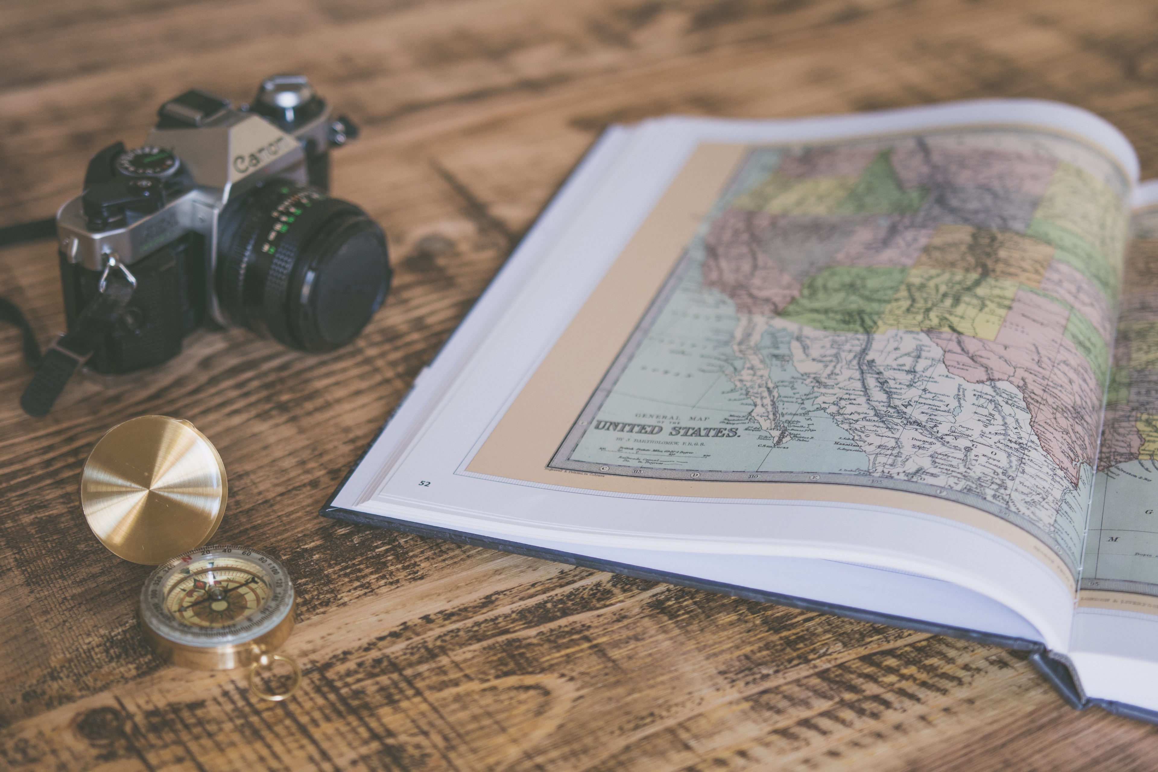 an open atlas with a map of the united states next to a camera and a compass on a wooden surface, never stop exploring 4k, HD Wallpaper