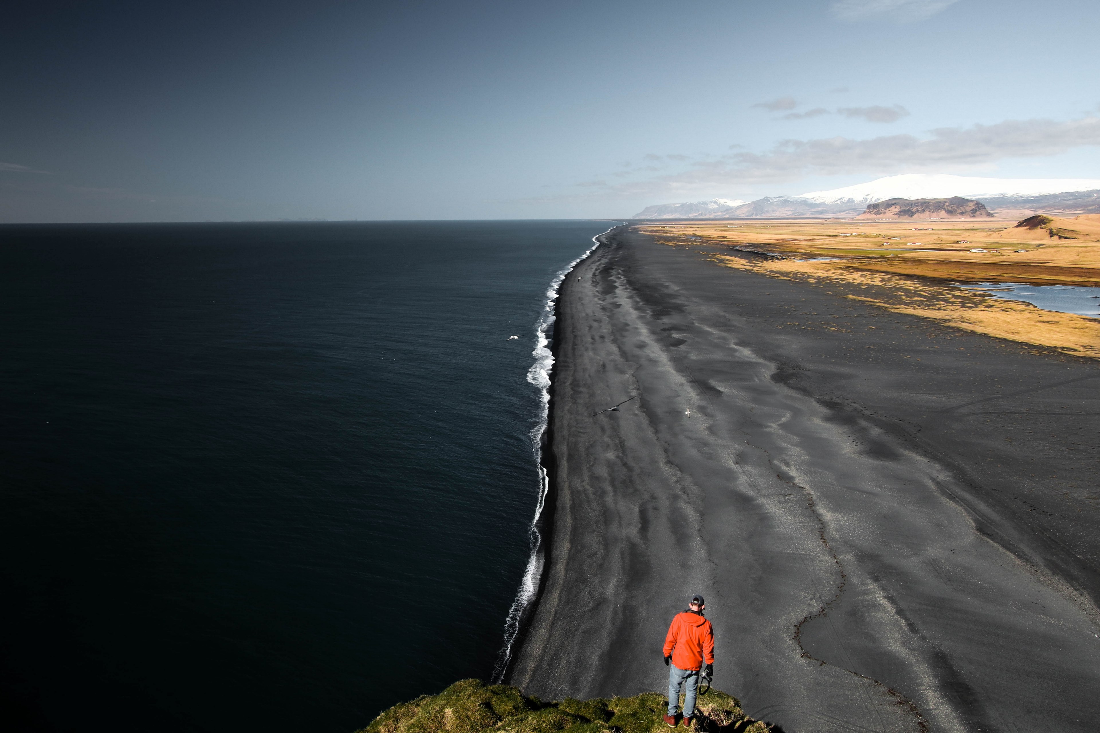 man standing on the rock looking at the black sand beach in vik, man looking at black beach 4k, HD Wallpaper