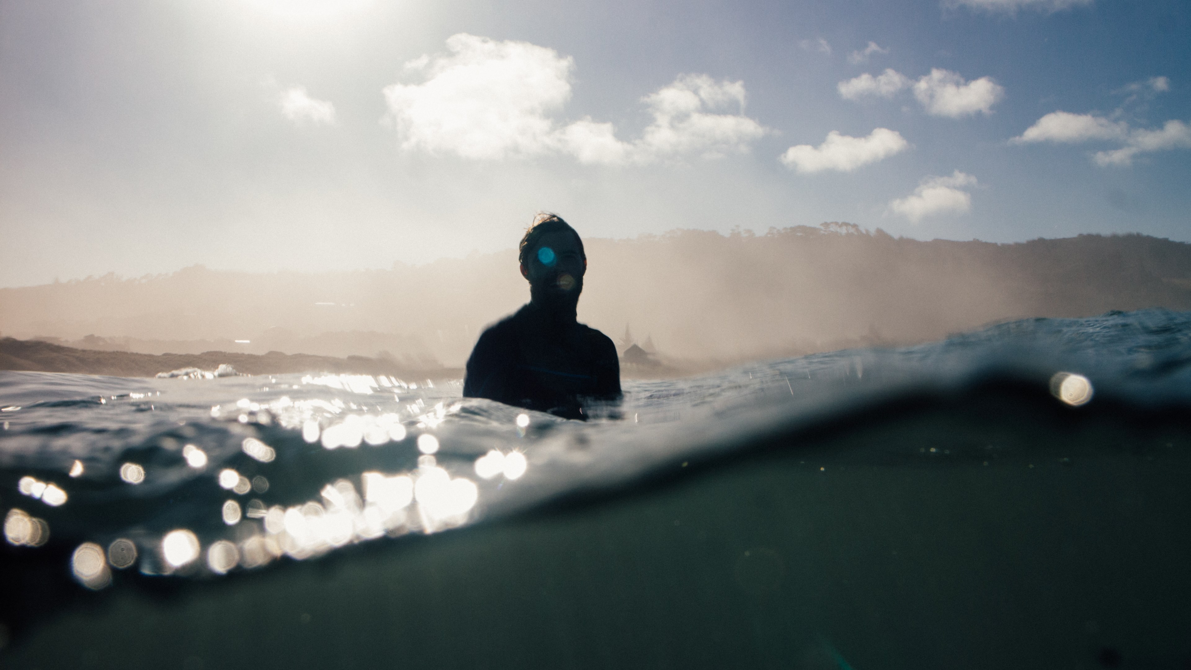 man silhouette in the water at muriwai beach, surfer and sea reflecting the sun 4k, HD Wallpaper
