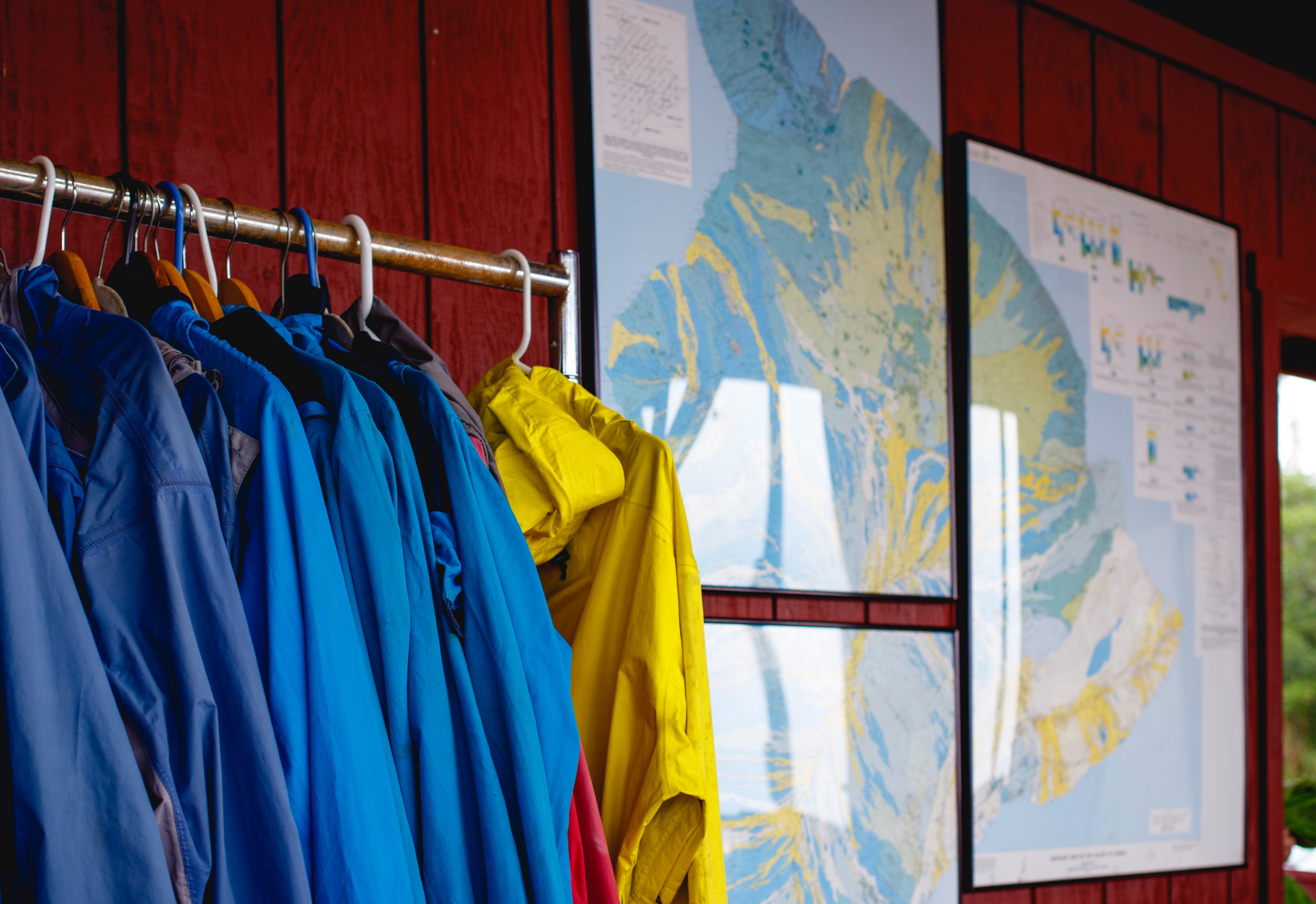 a rack of raincoats next to several framed maps hanging on a red paneled wall, you are here 4k, HD Wallpaper