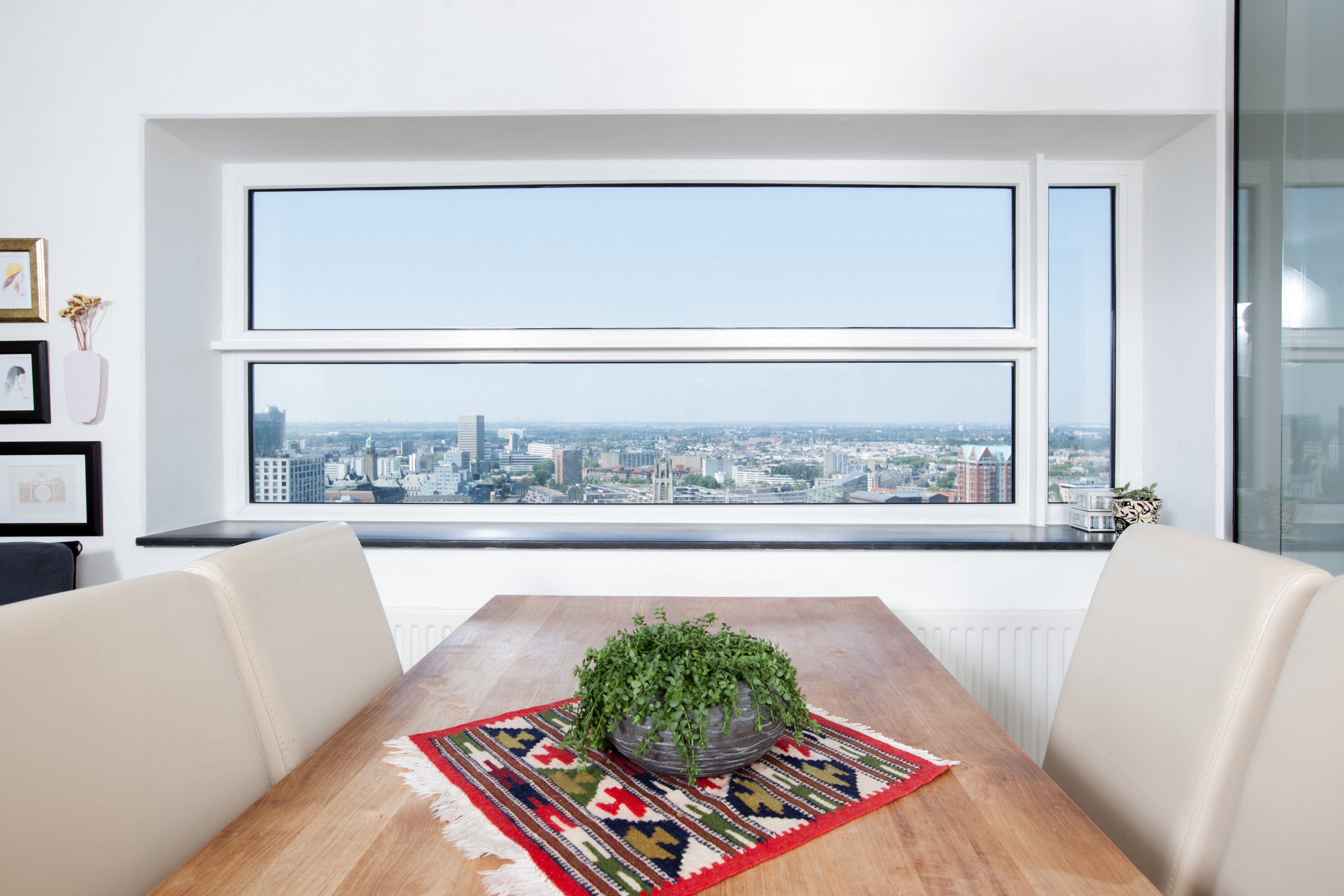 a potted plant on a table in a room with a wide window looking out on the city, dining with a view 4k, HD Wallpaper