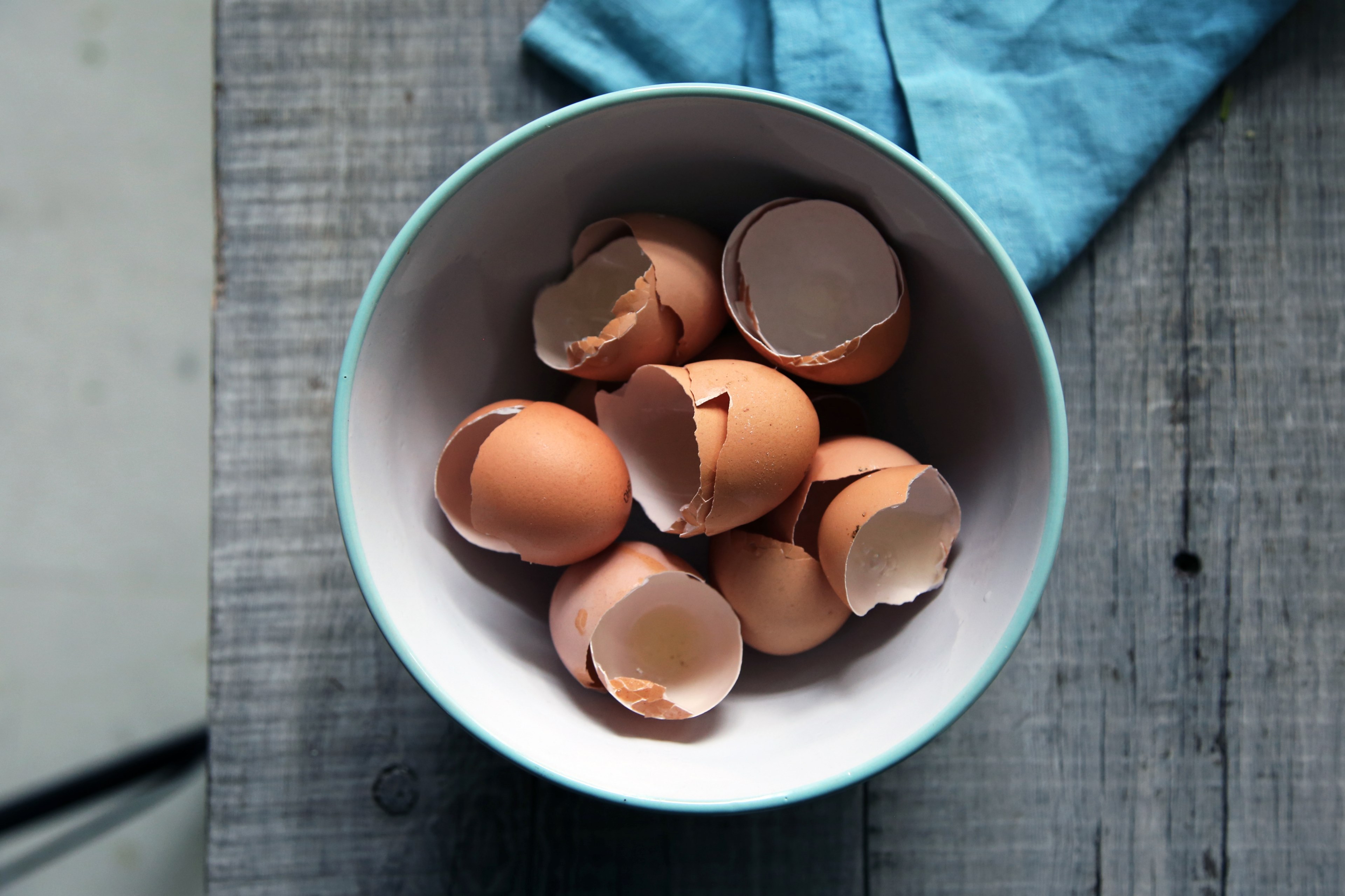 a bowl full of cracked eggshells on a wooden table, cracked egg shells 4k, HD Wallpaper