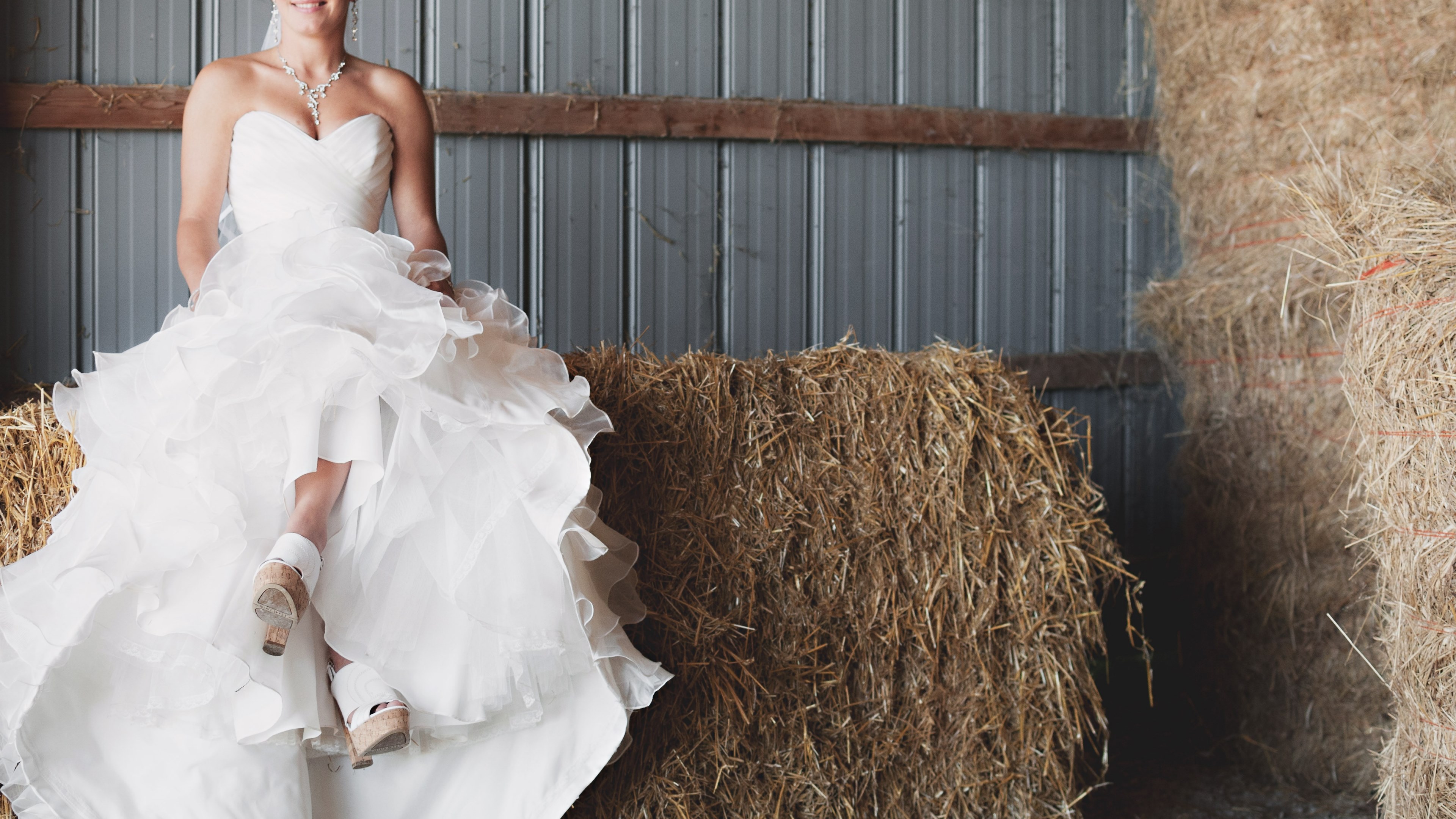 happy bride in a wedding gown sits atop bales of hay in a barn, bride in hay barn london 4k, HD Wallpaper
