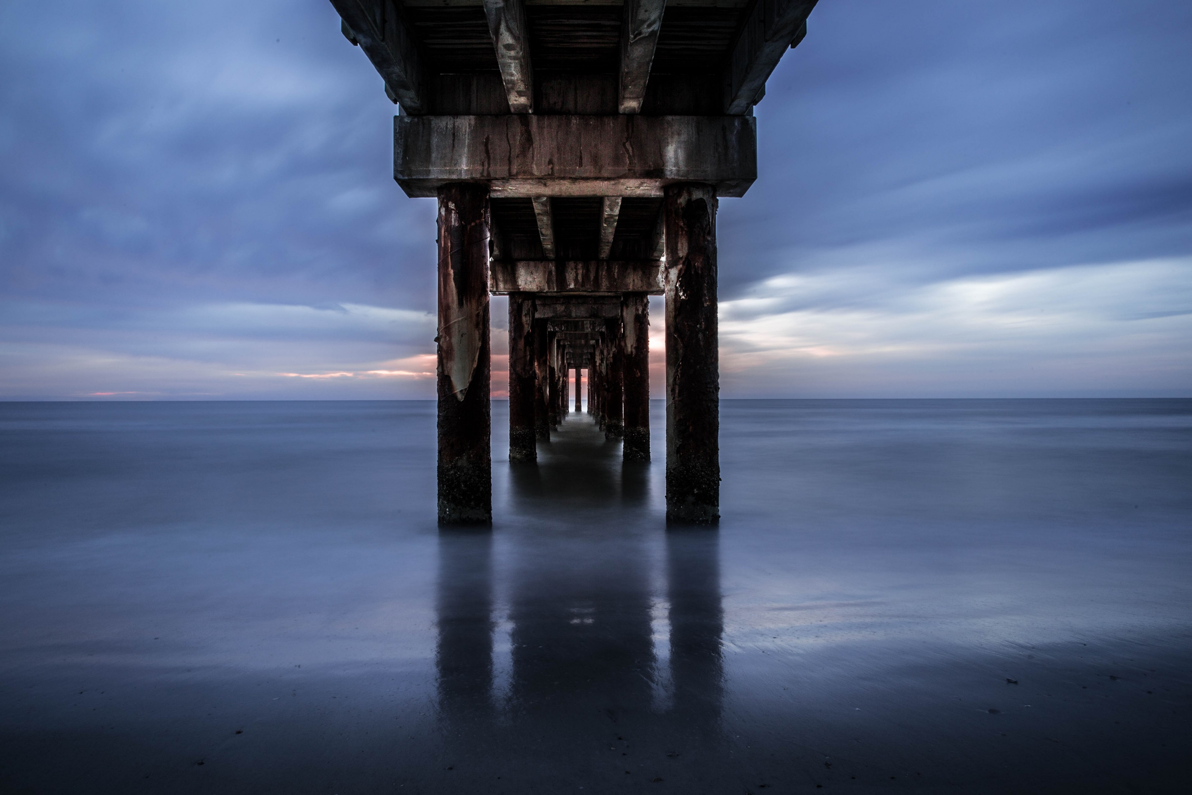 view into the distance under the pier between the pillars at saint augustine beach, sunrise through the pier 4k, HD Wallpaper