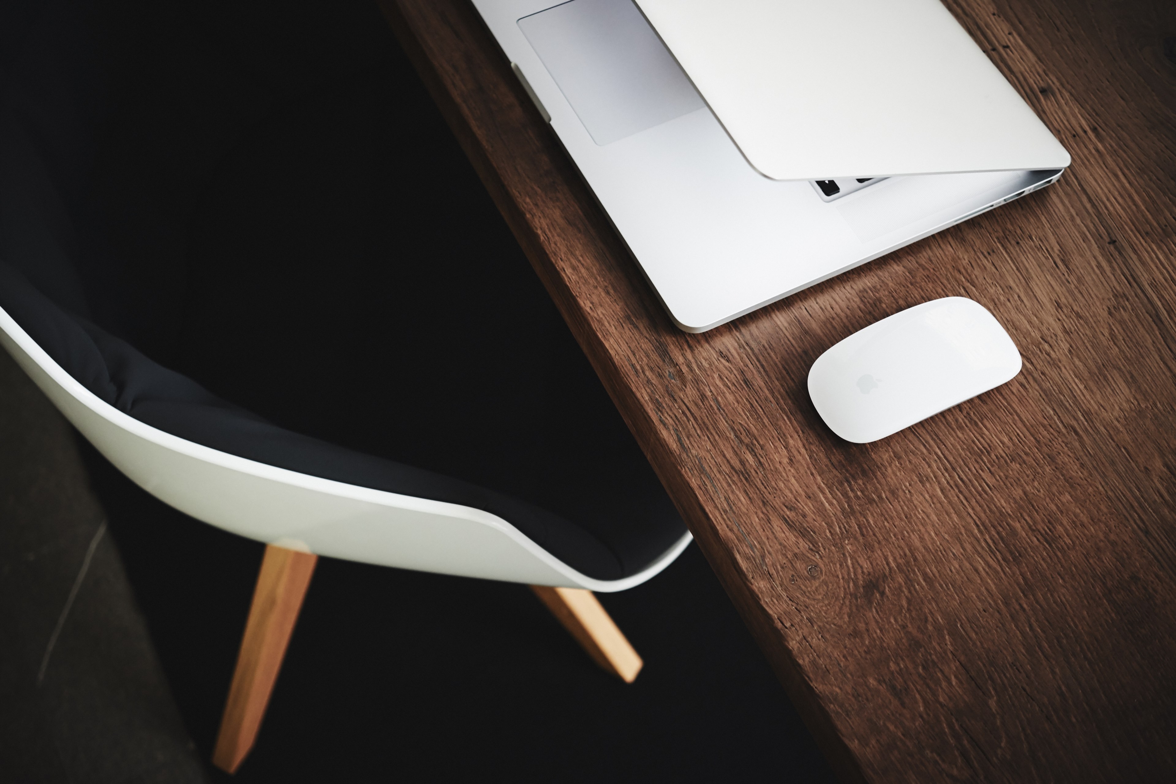 an overhead shot of a mouse and a half closed macbook on an elegant wooden desk, half closed laptop 4k, HD Wallpaper