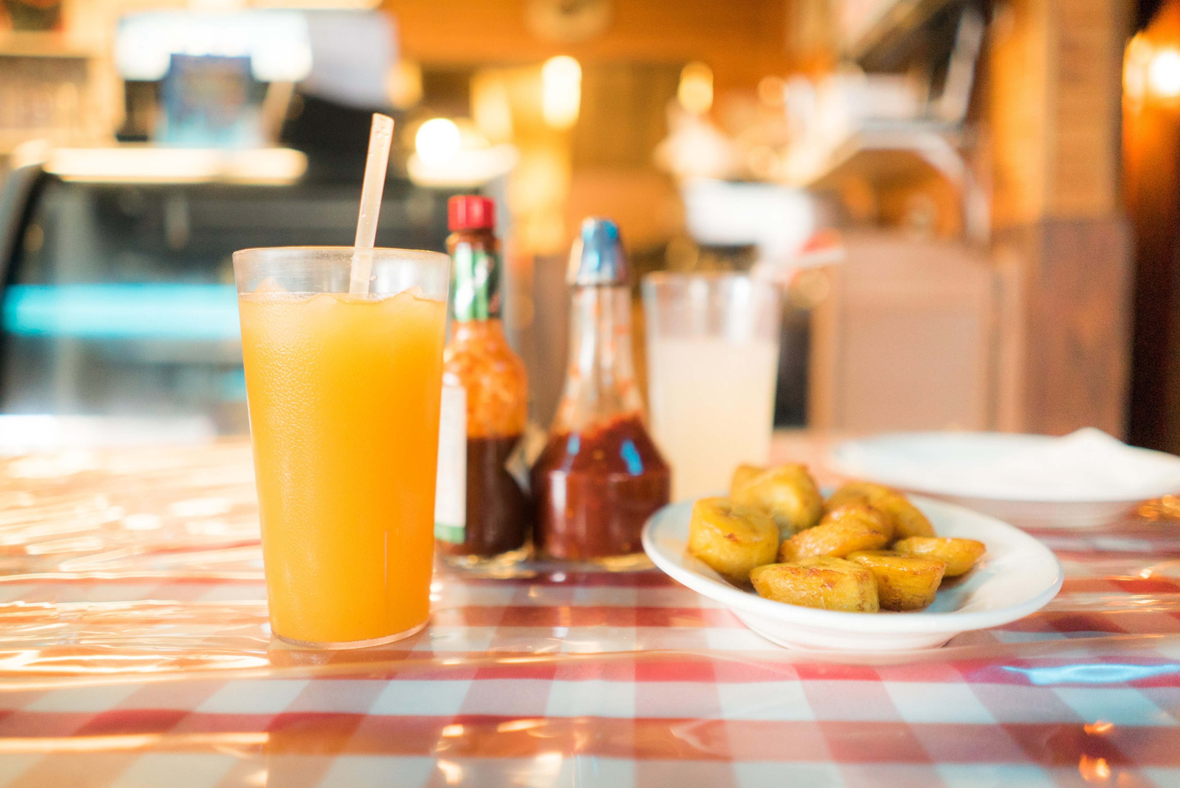 fried potatoes next to a glass of juice and sauce bottles on a restaurant table, dominican restaurant 4k, HD Wallpaper