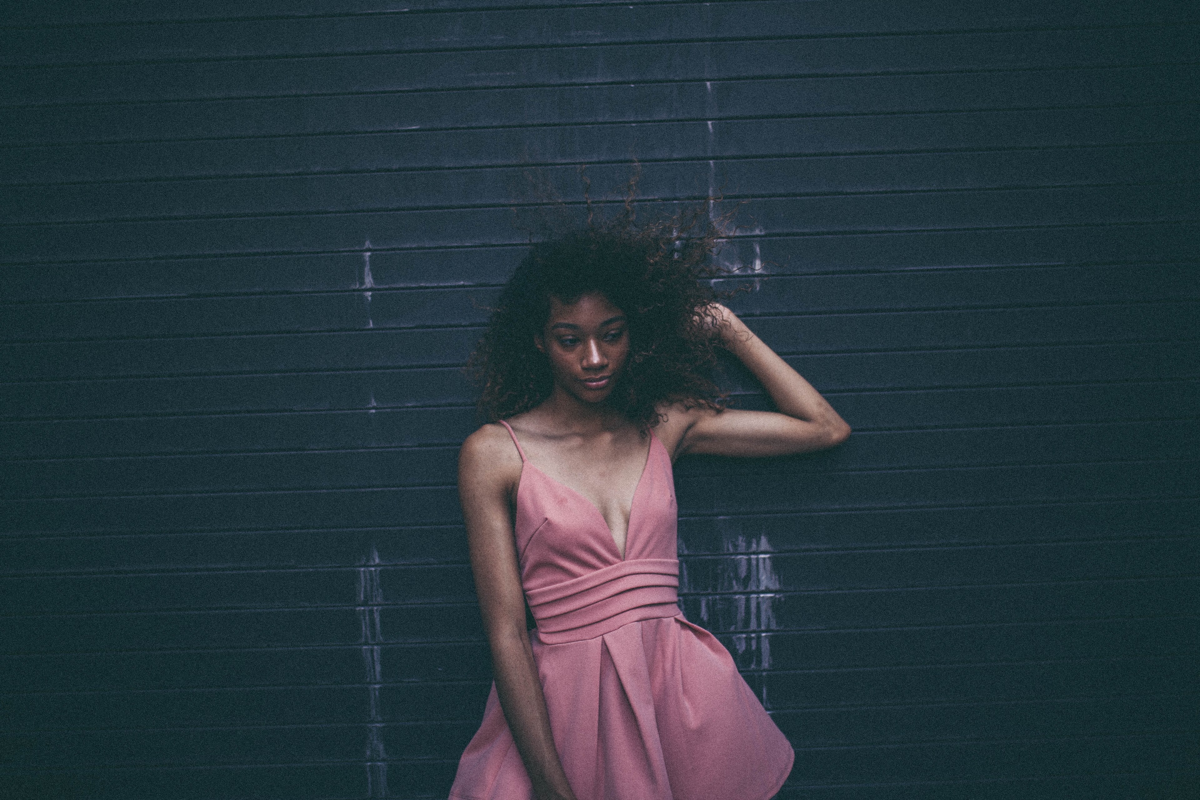 woman in a pink cocktail dress looks unsure posed against a garage door, smug face 4k, HD Wallpaper
