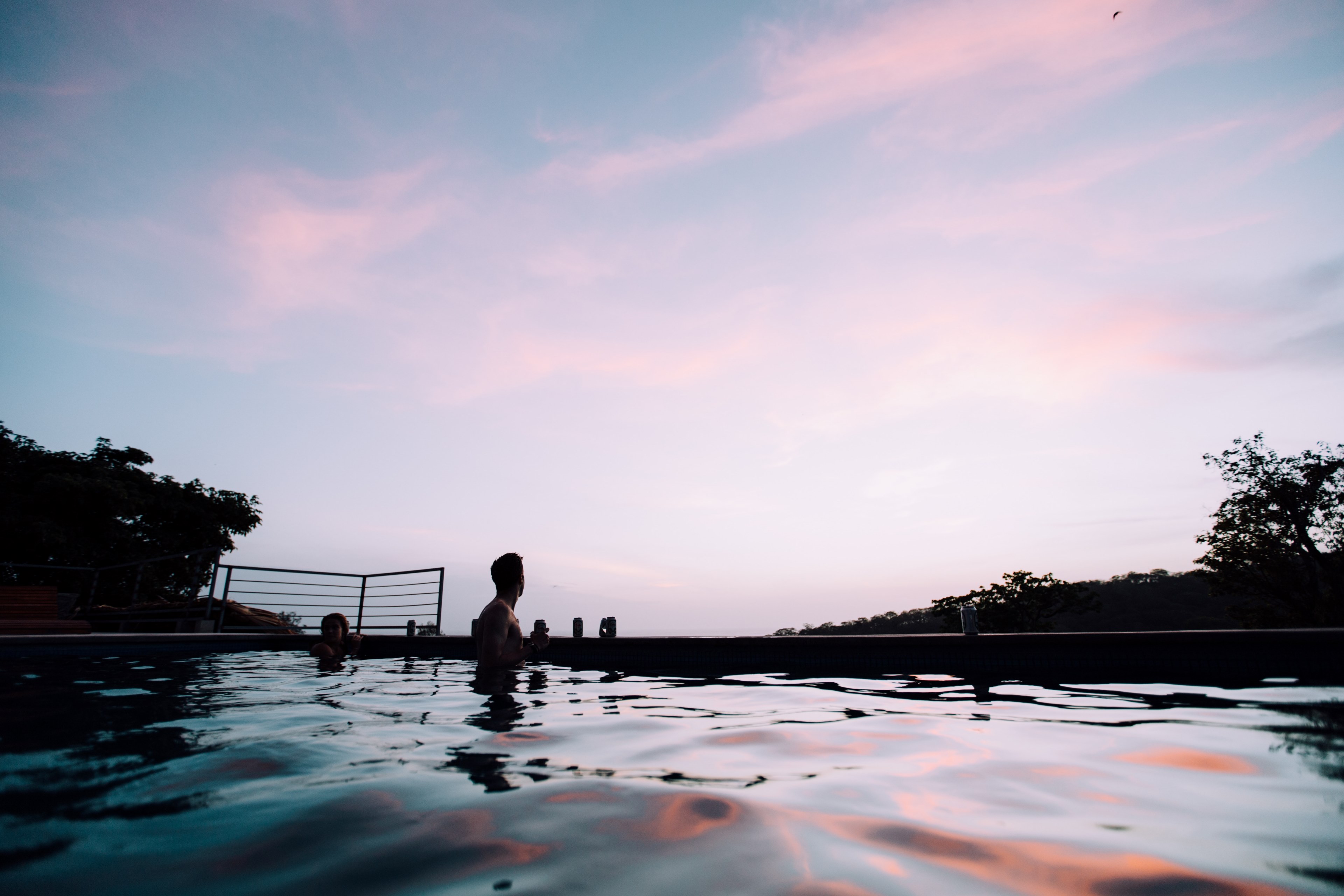 man swimming in a pool at hulakai hotel and ecological community gazing at a pink and blue sunset sky, man in a swimming pool 4k, HD Wallpaper