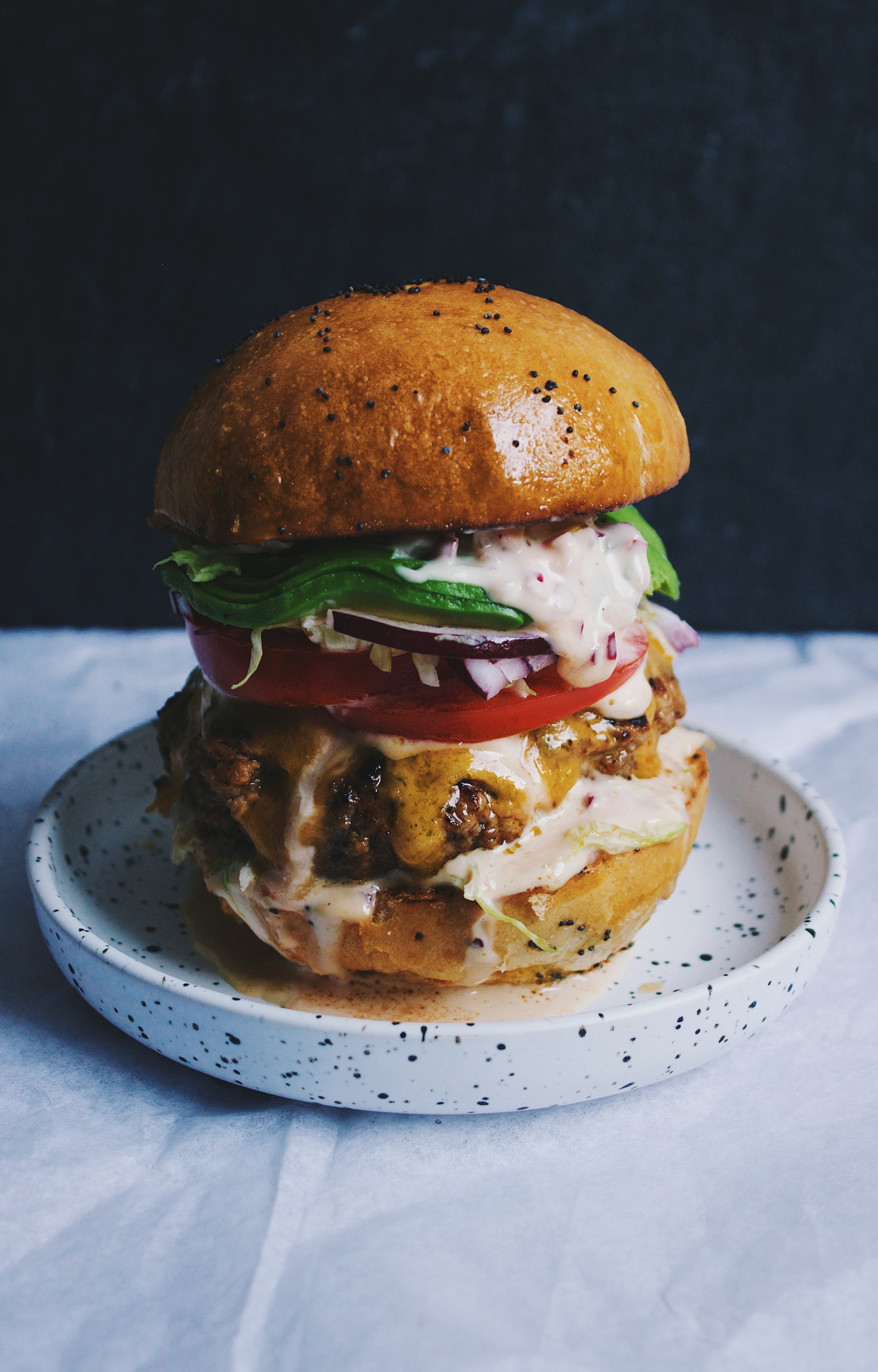 a cheeseburger with lettuce tomato onions and avocado on a small plate in limassol, burger heaven 4k, Phone HD Wallpaper
