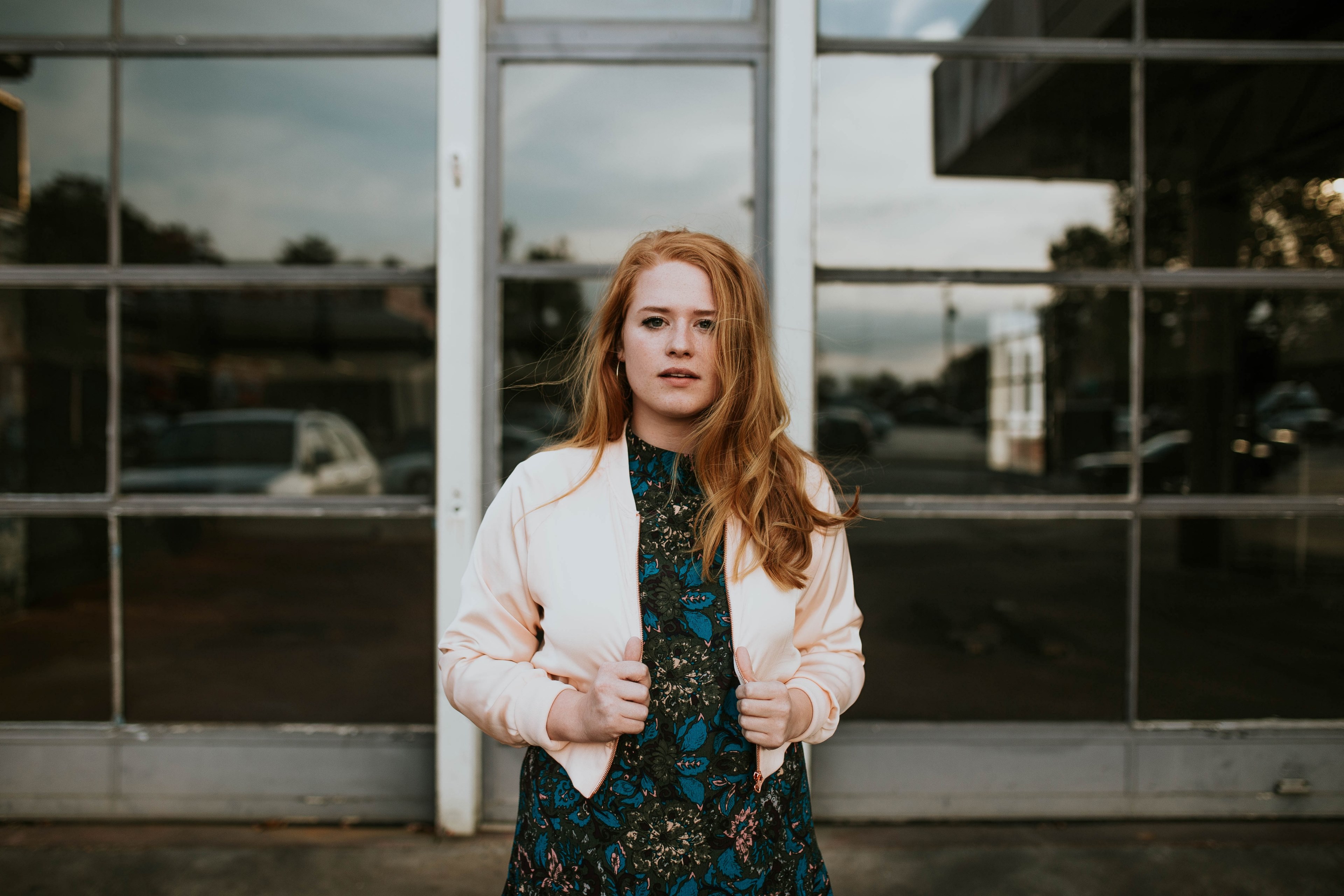 a woman with red hair looks at the camera in front of a reflective glass window, woman in front of window 4k, HD Wallpaper