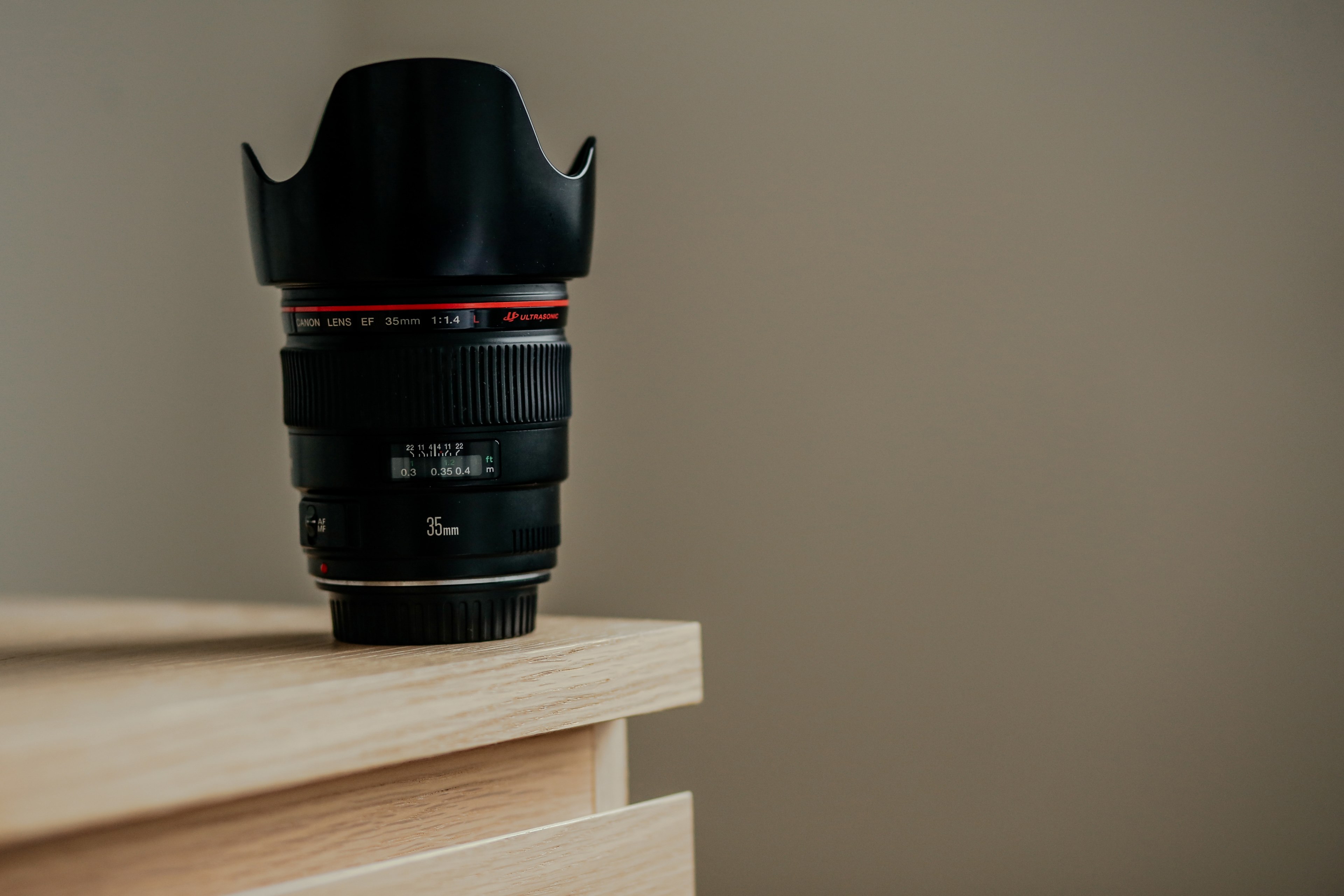 a long camera lens on the edge of a wooden surface, lens and hood on desk corner 4k, HD Wallpaper