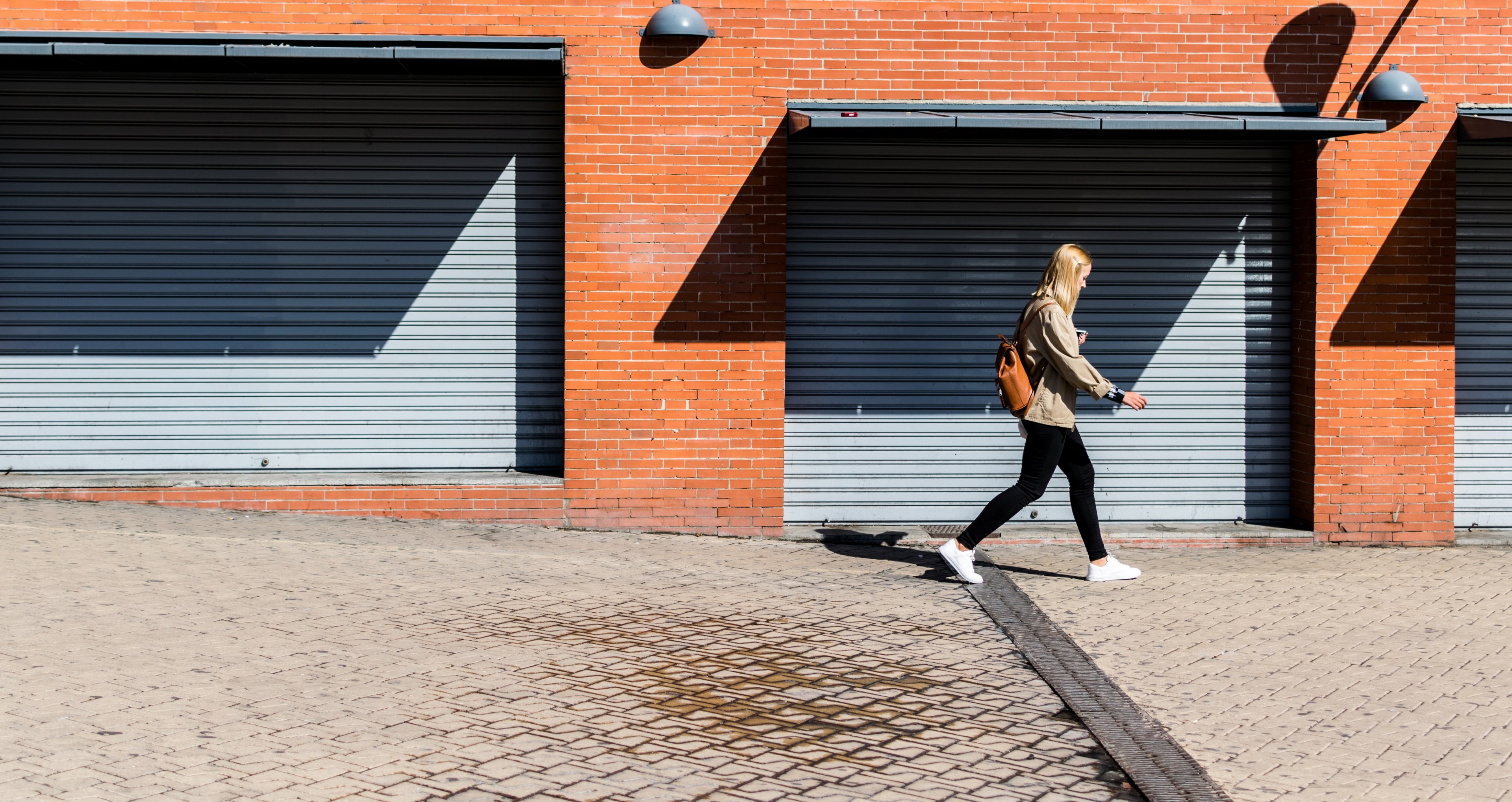 a woman is walking past a brick building at the madrid atocha railway station, _walking between walls 4k, HD Wallpaper