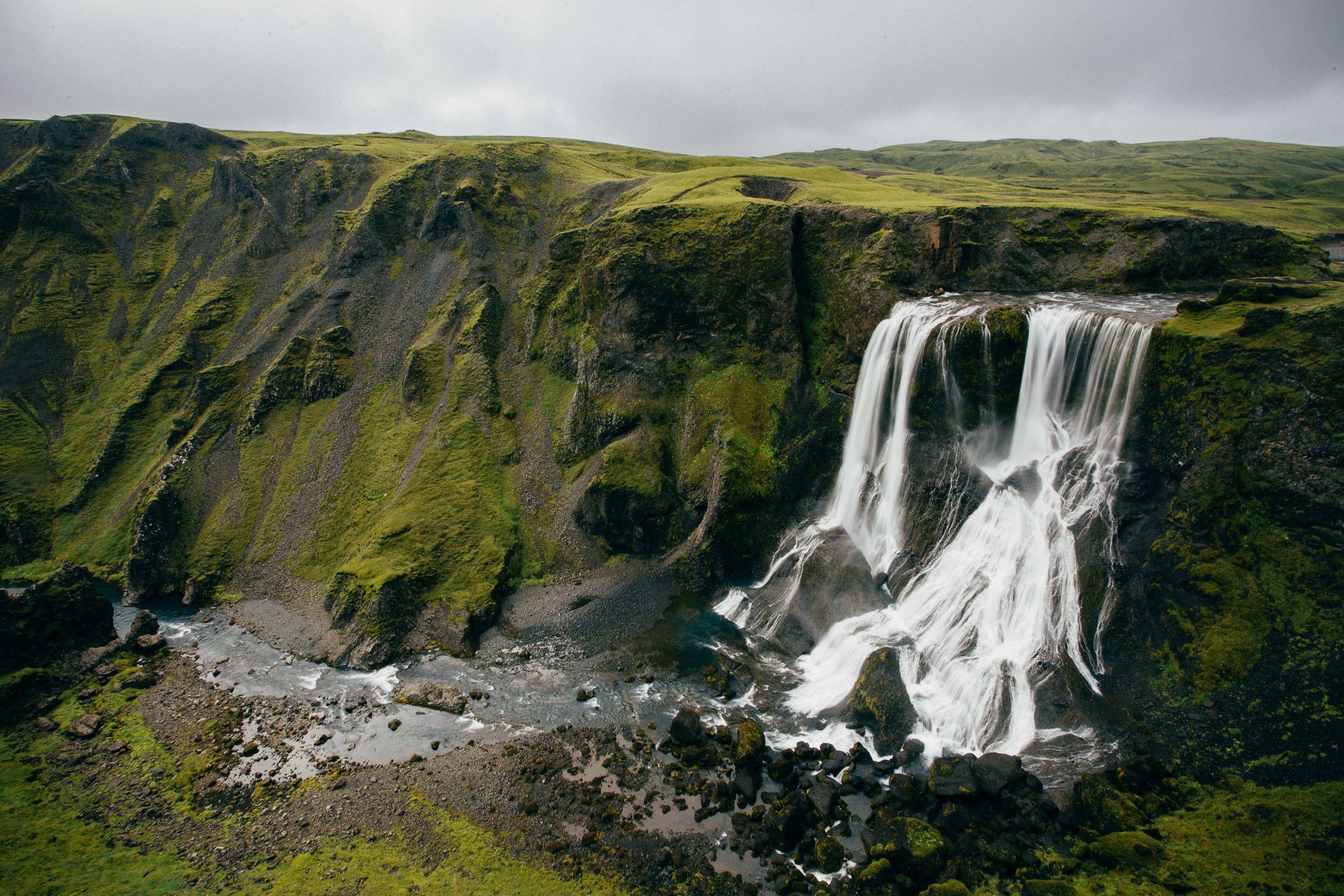 waterfall rushing down a green mossy cliff with a grey cloudy sky in the background, mossy rock mountain and waterfall 4k, HD Wallpaper