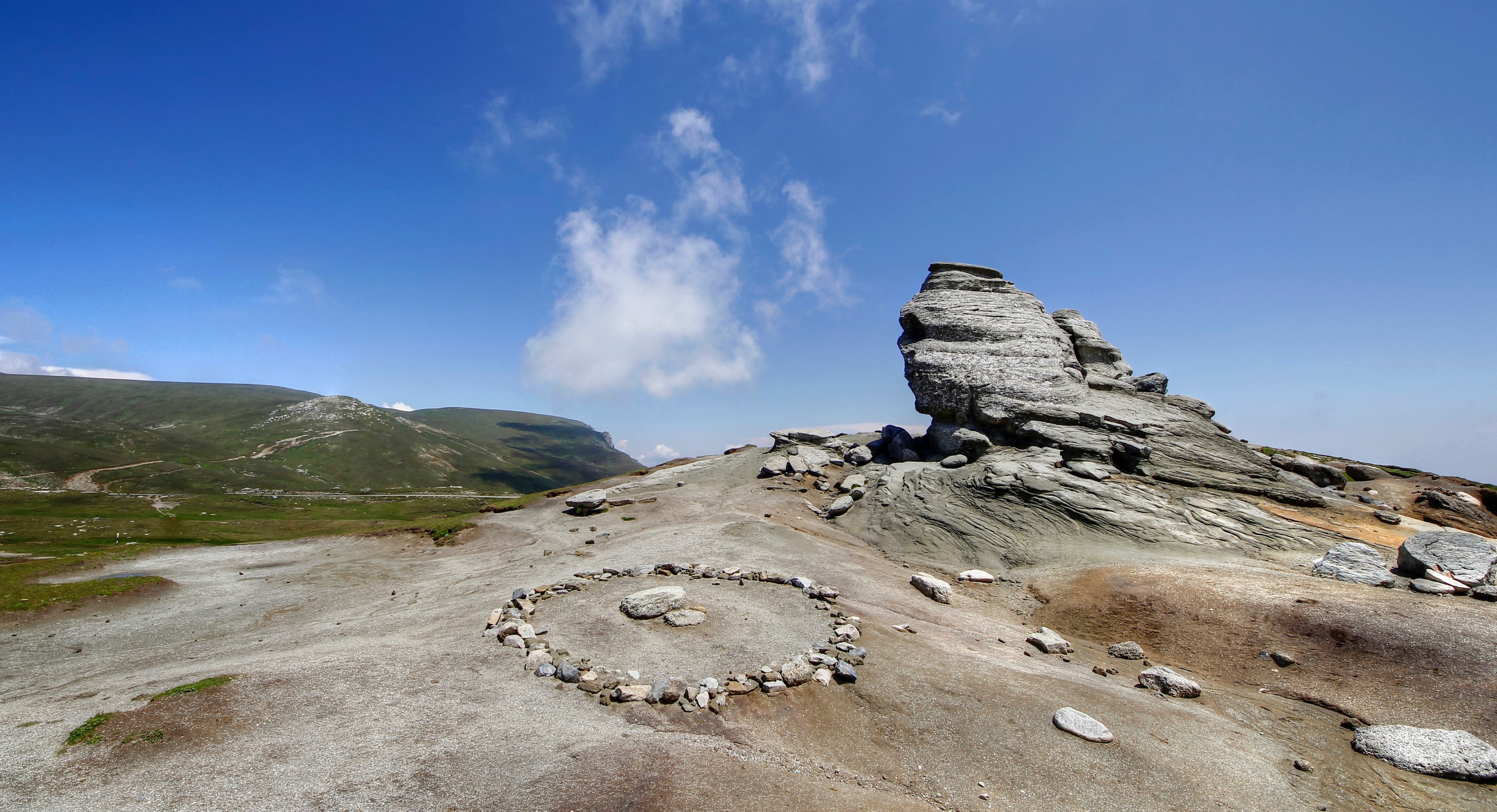 a circle made of pebbles next to a rough rocky outcrop with green hills in the background, pebble circle and a rock 4k, HD Wallpaper