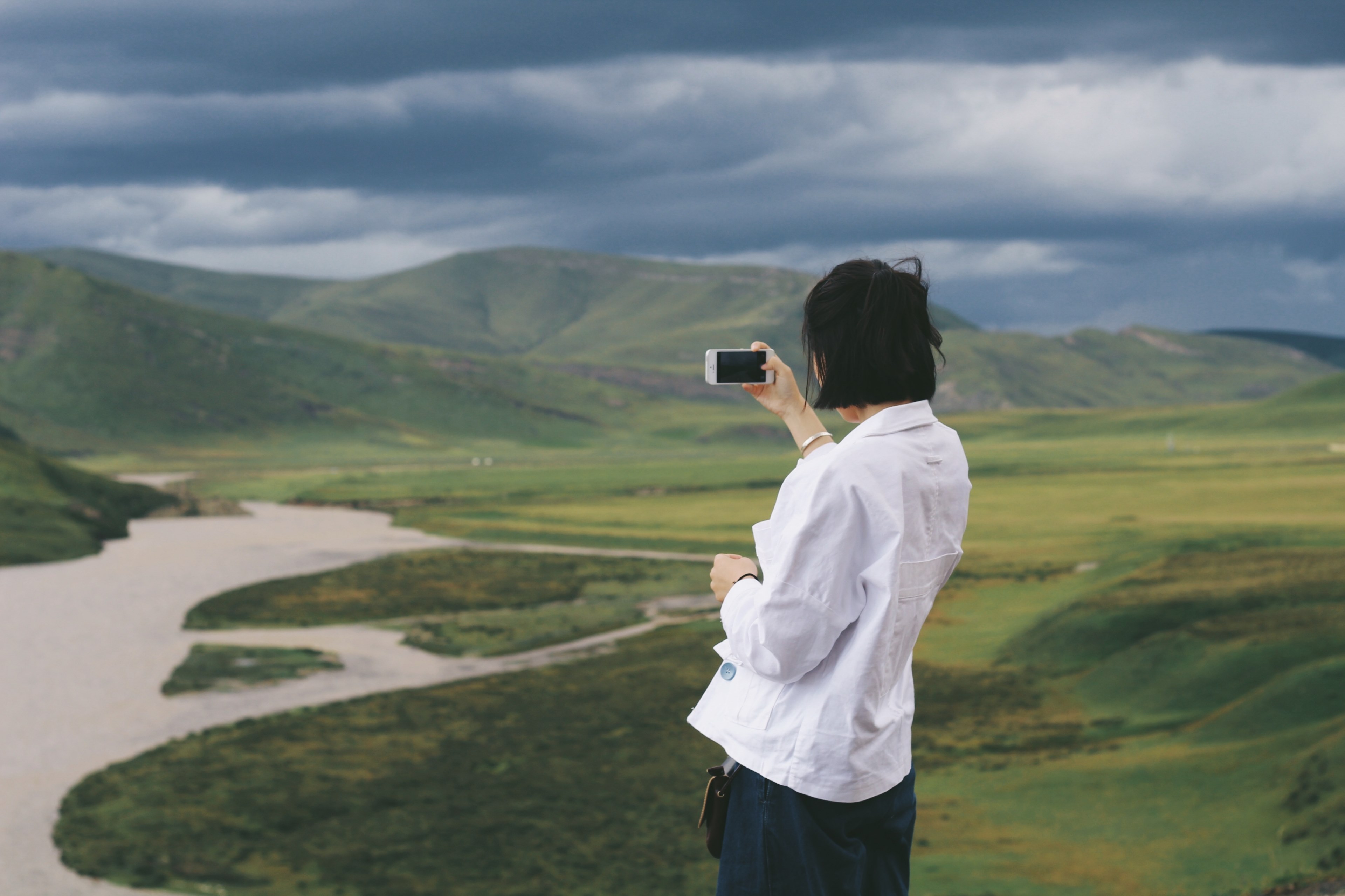 person in white shirt using a smartphone to photograph green hills and river, taking photo of hills 4k, HD Wallpaper