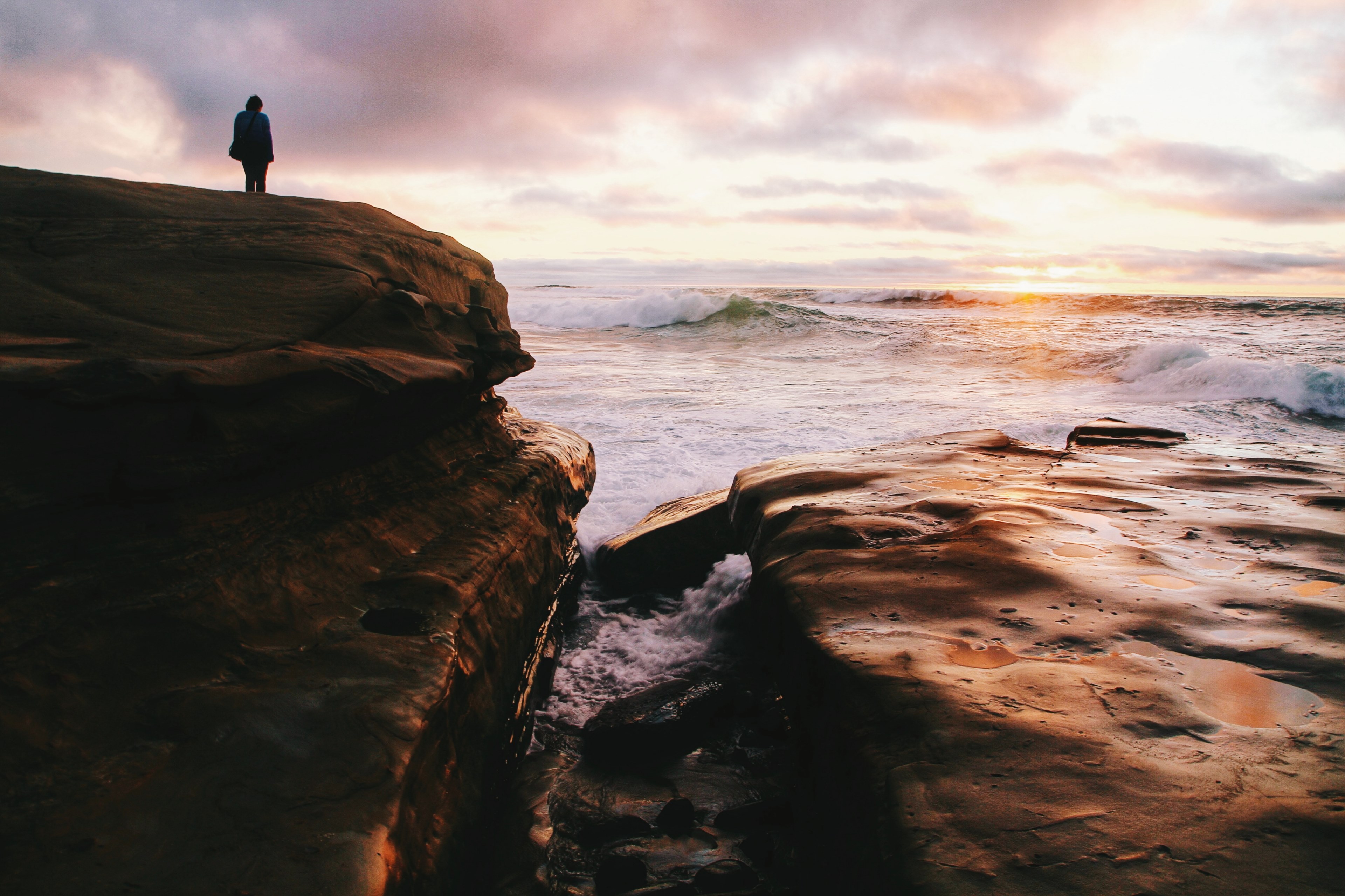 silhouette person standing on coastline rock with white water ocean braking below, ocean shaped coastline and silhouette person 4k, HD Wallpaper
