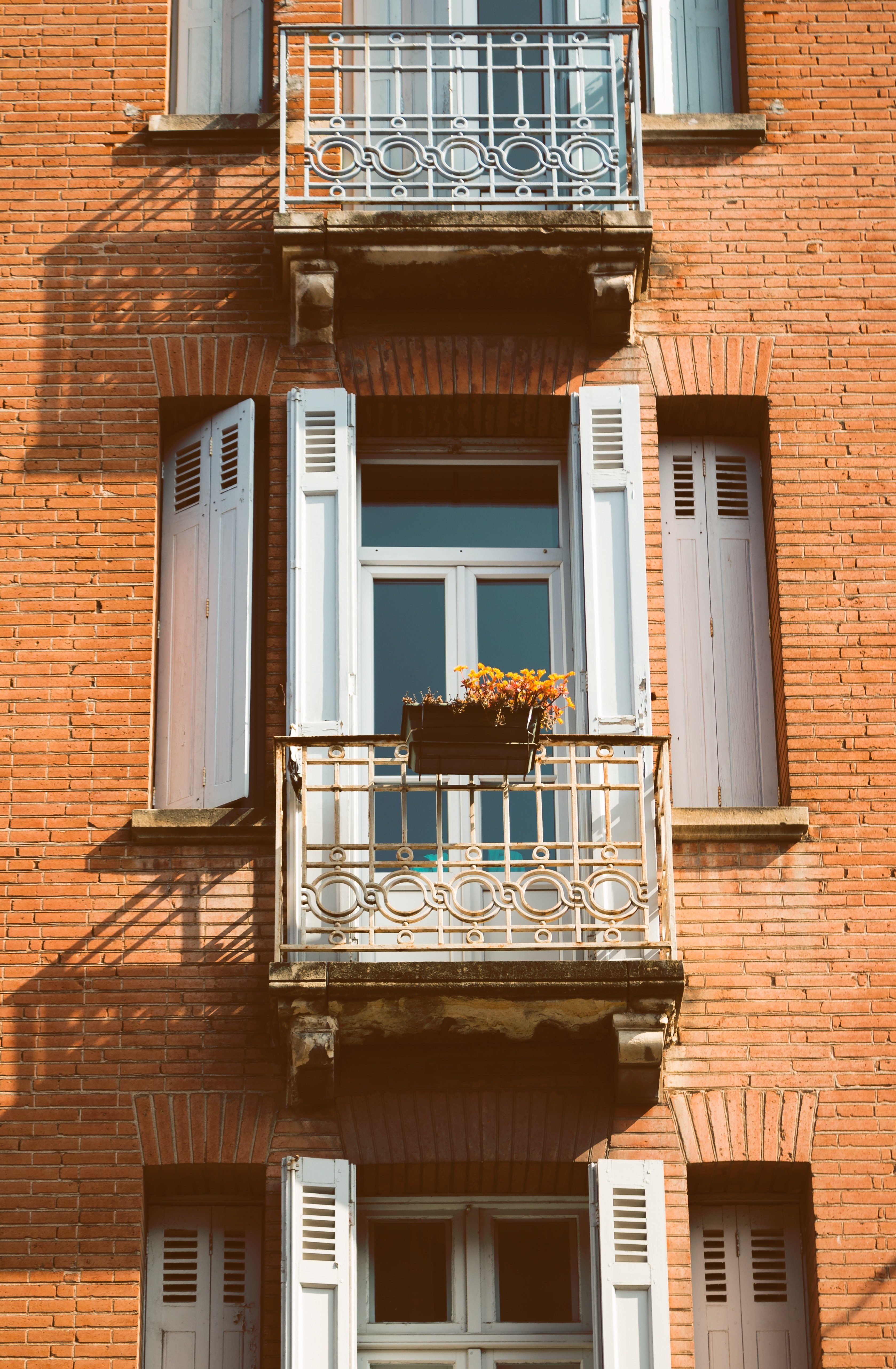 a brick building with large windows that have white shutters and balconies with flower planters on them, brick building with shutters 4k, Phone HD Wallpaper