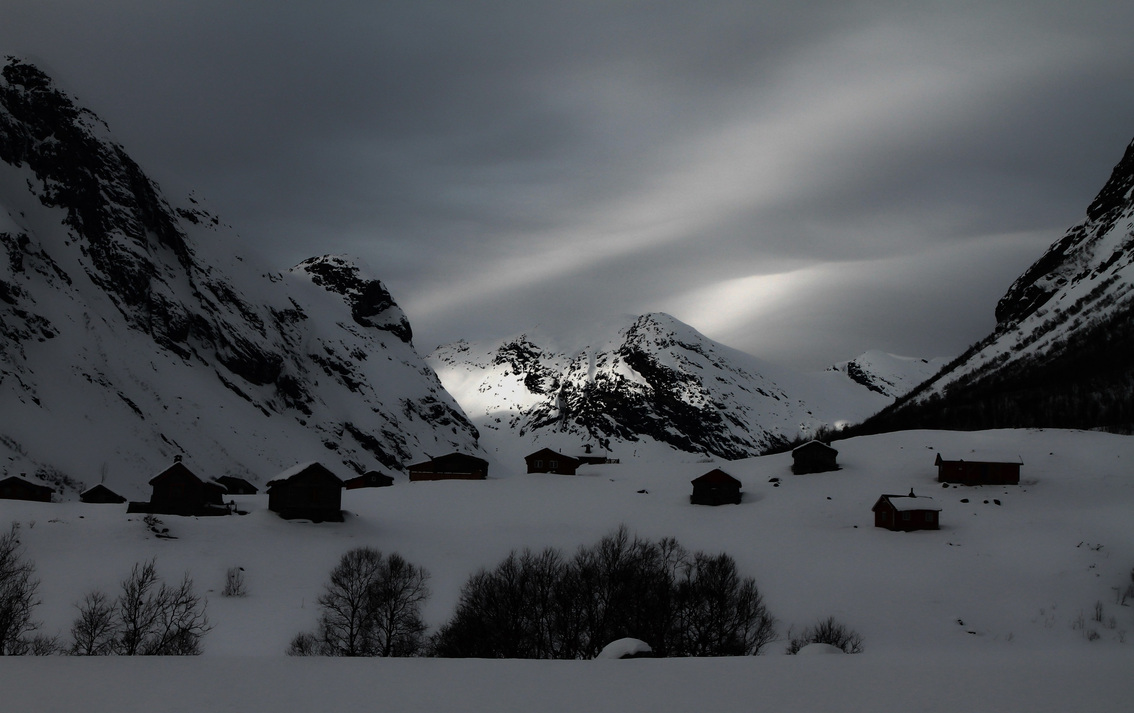 a dim shot of small buildings between snow topped mountains in strynefjellet, gloomy mountain village 4k, HD Wallpaper