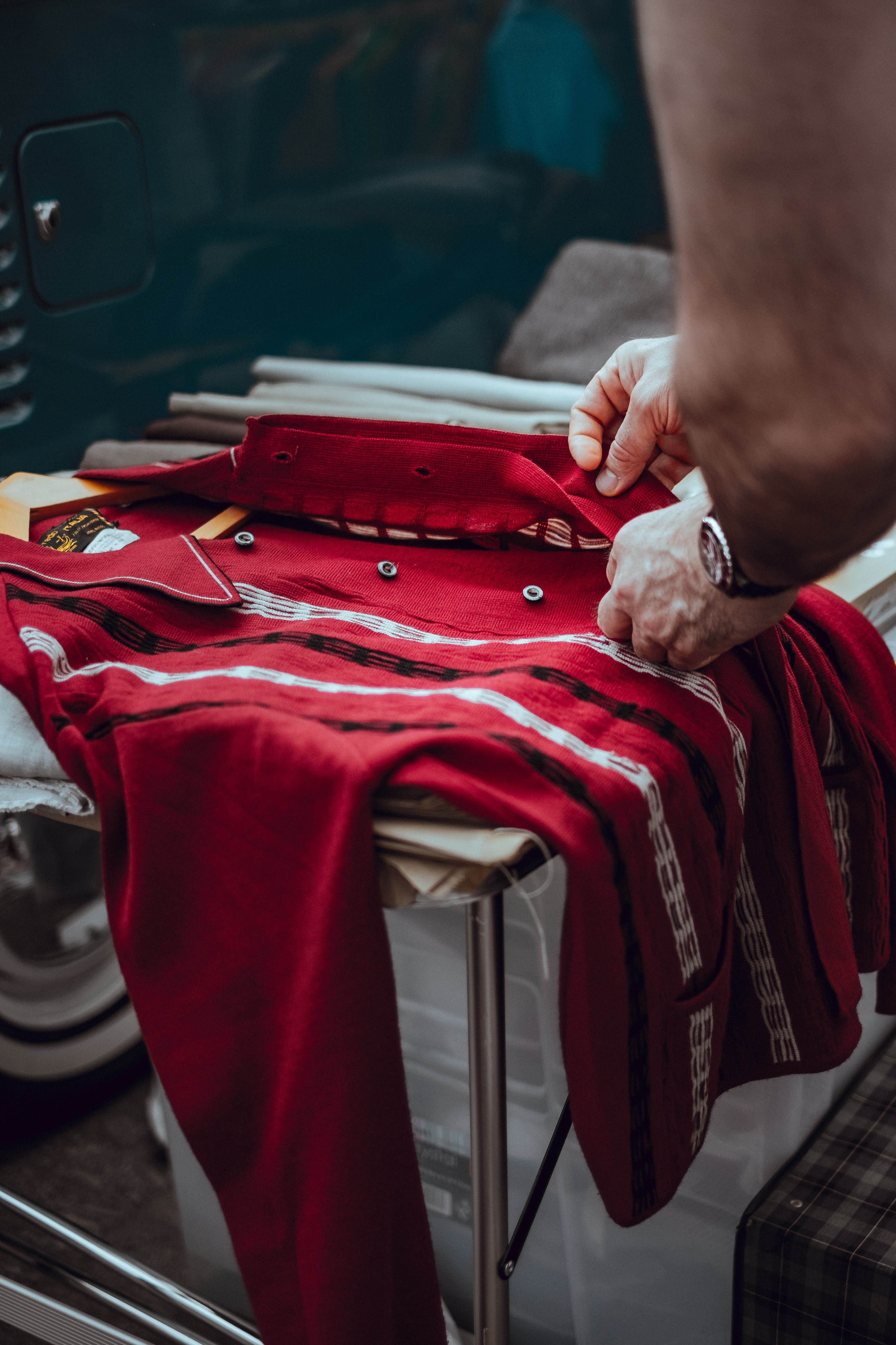 a person examines a red vintage garment on a table in lewis cubitt square, retro red jumper 4k, Phone HD Wallpaper