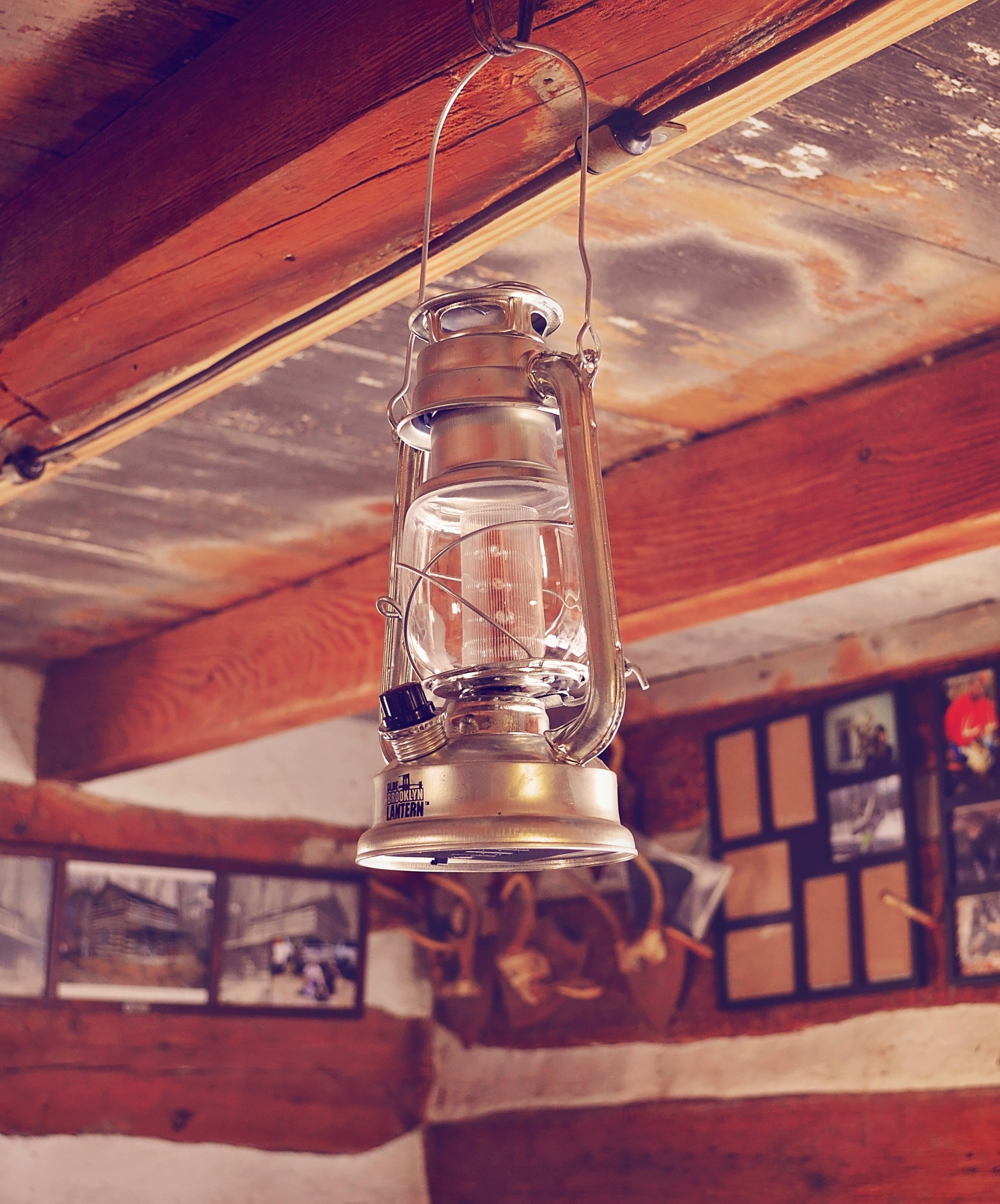 an old rustic lantern hangs in a wooden lodge with photos on the walls, camping in style 4k, Phone HD Wallpaper