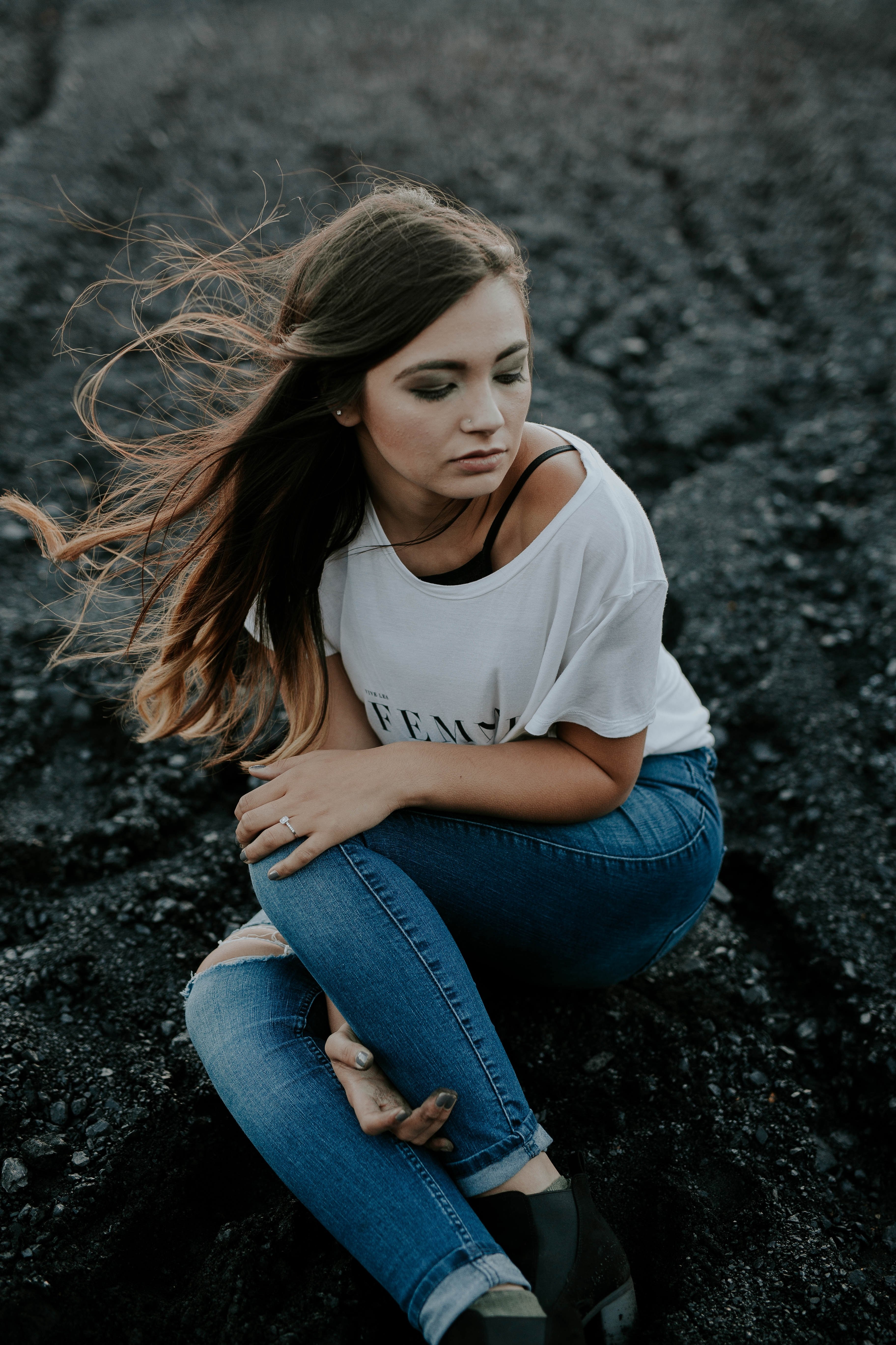 young woman holding her knees while sitting on a black sand beach, alone at the beach 4k, Phone HD Wallpaper