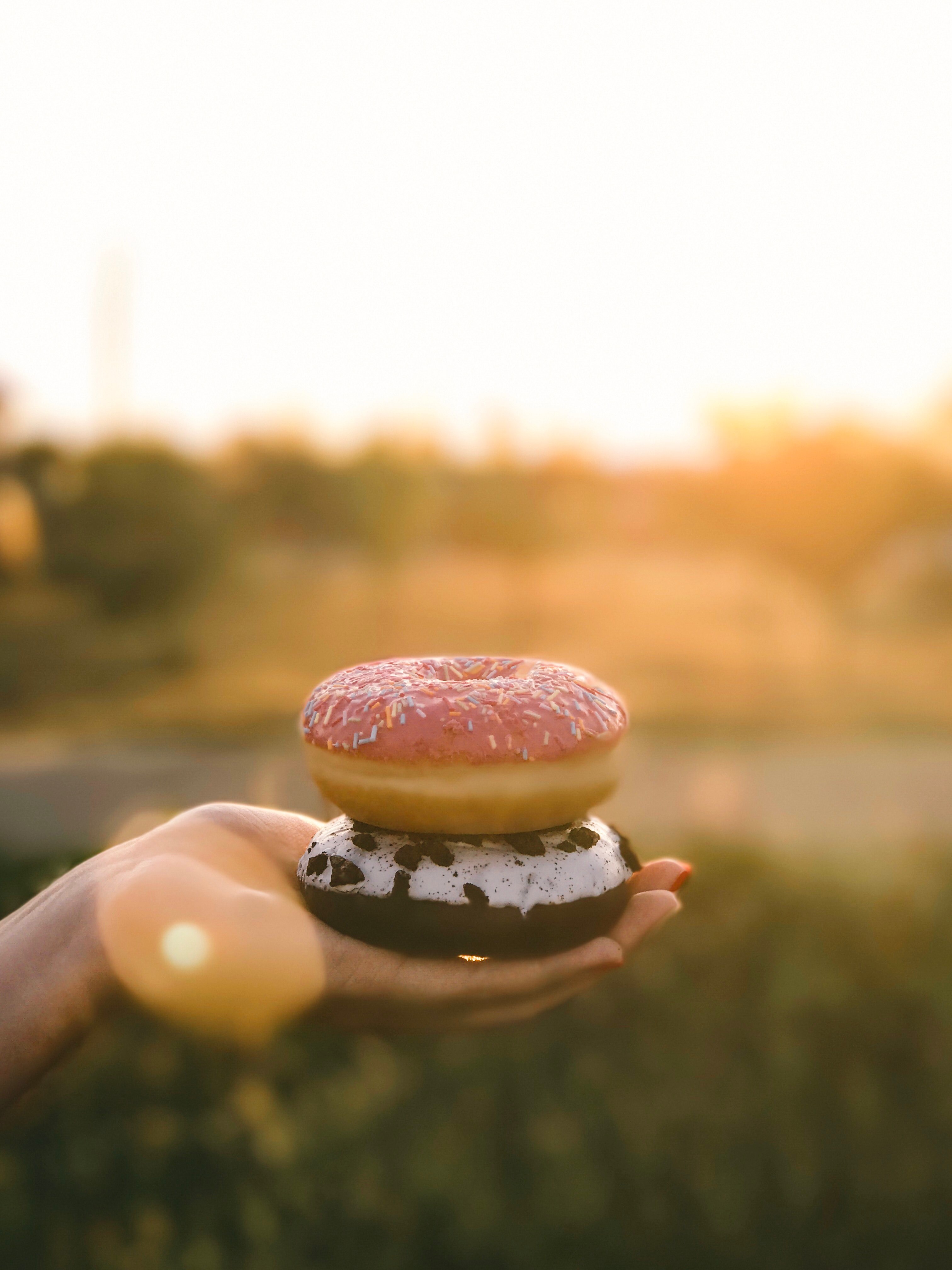 a person holding two donuts outside, _holding donuts in hand 4k, Phone HD Wallpaper