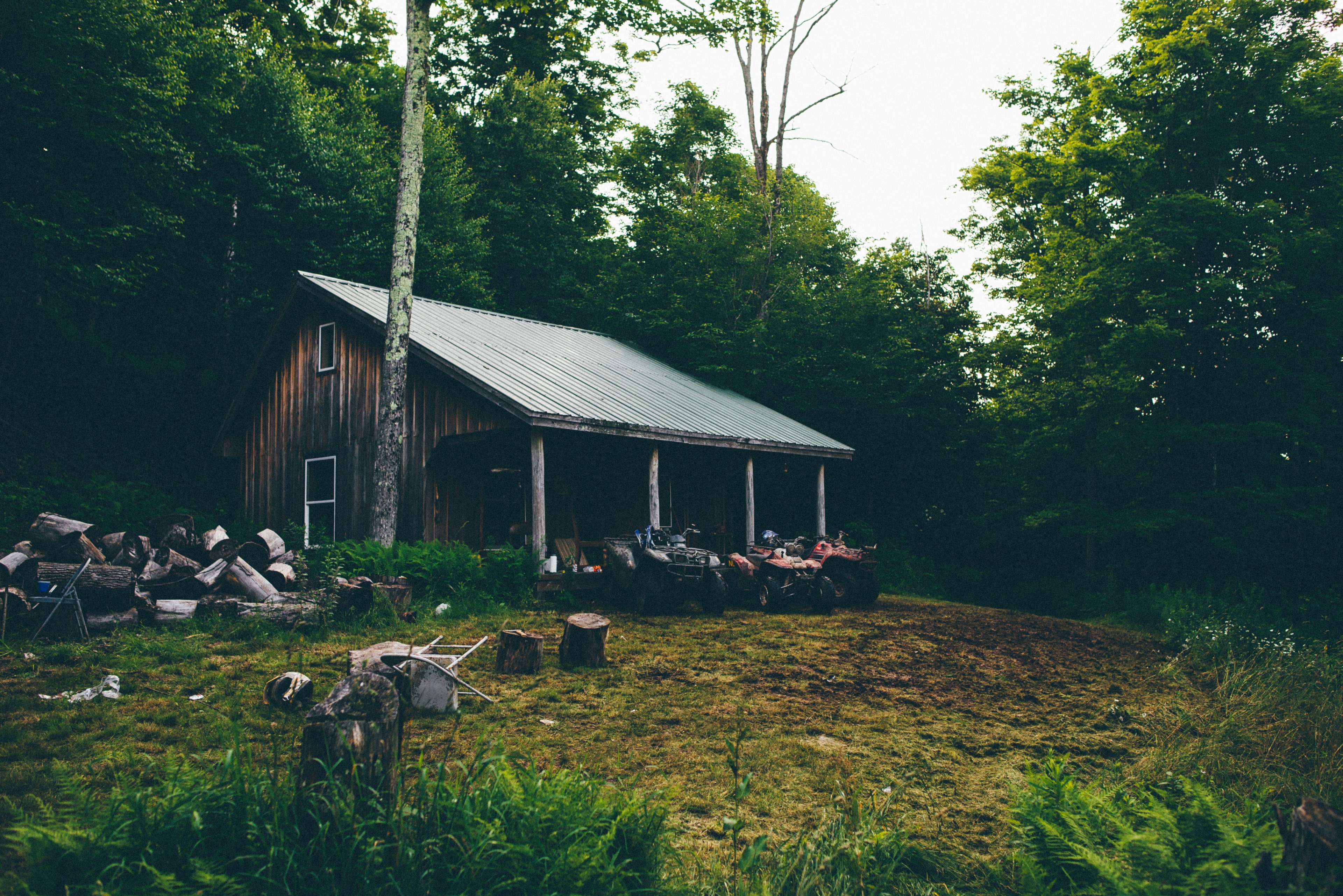 old cabin in the woods with a tin roof and three four wheelers lawn chairs and chopped wood in the yard, cabin in the woods 4k, HD Wallpaper