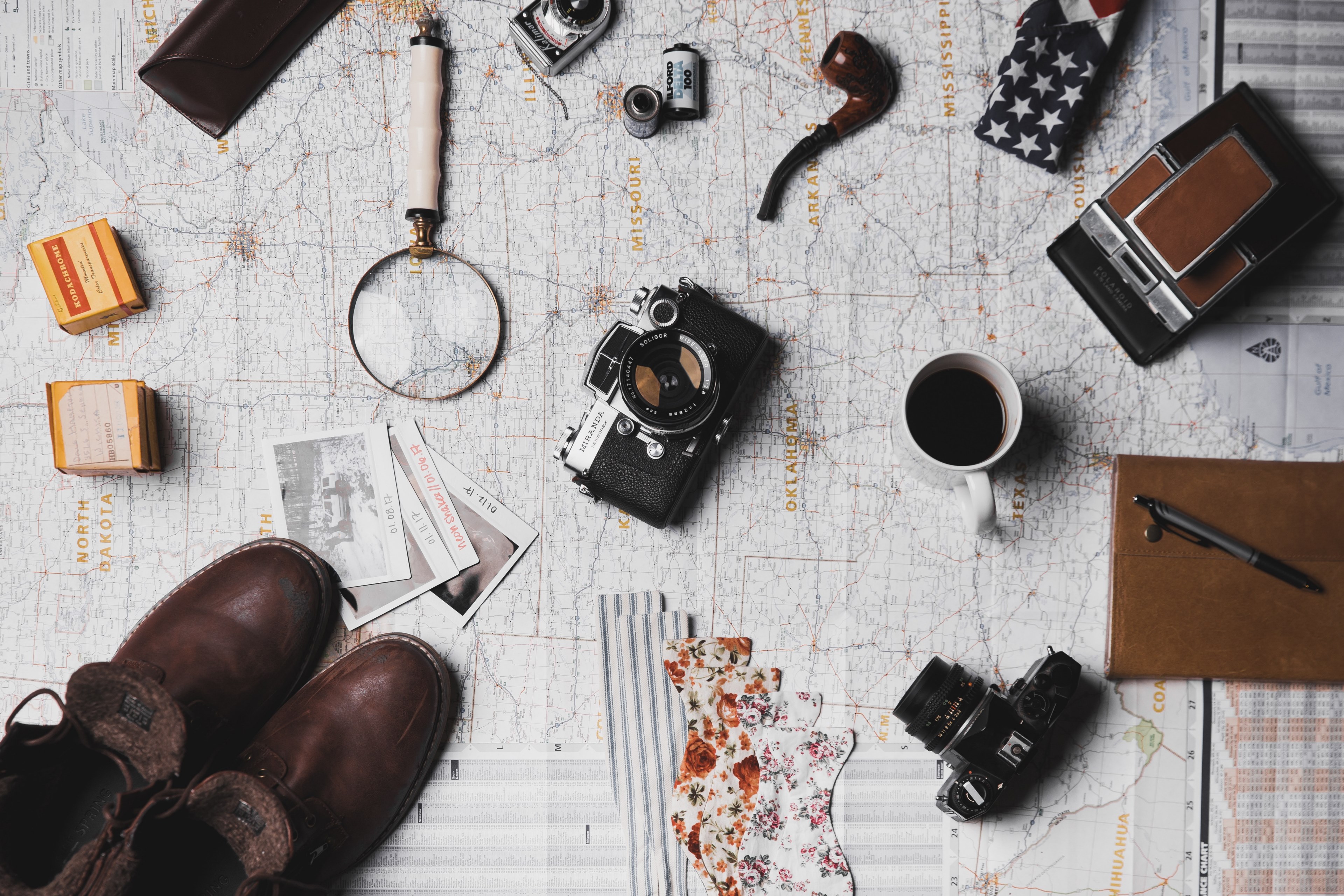a flatlay of a magnifying glass a cup of coffee cameras photos and various travel items on a map, the plan before the adventure 4k, HD Wallpaper