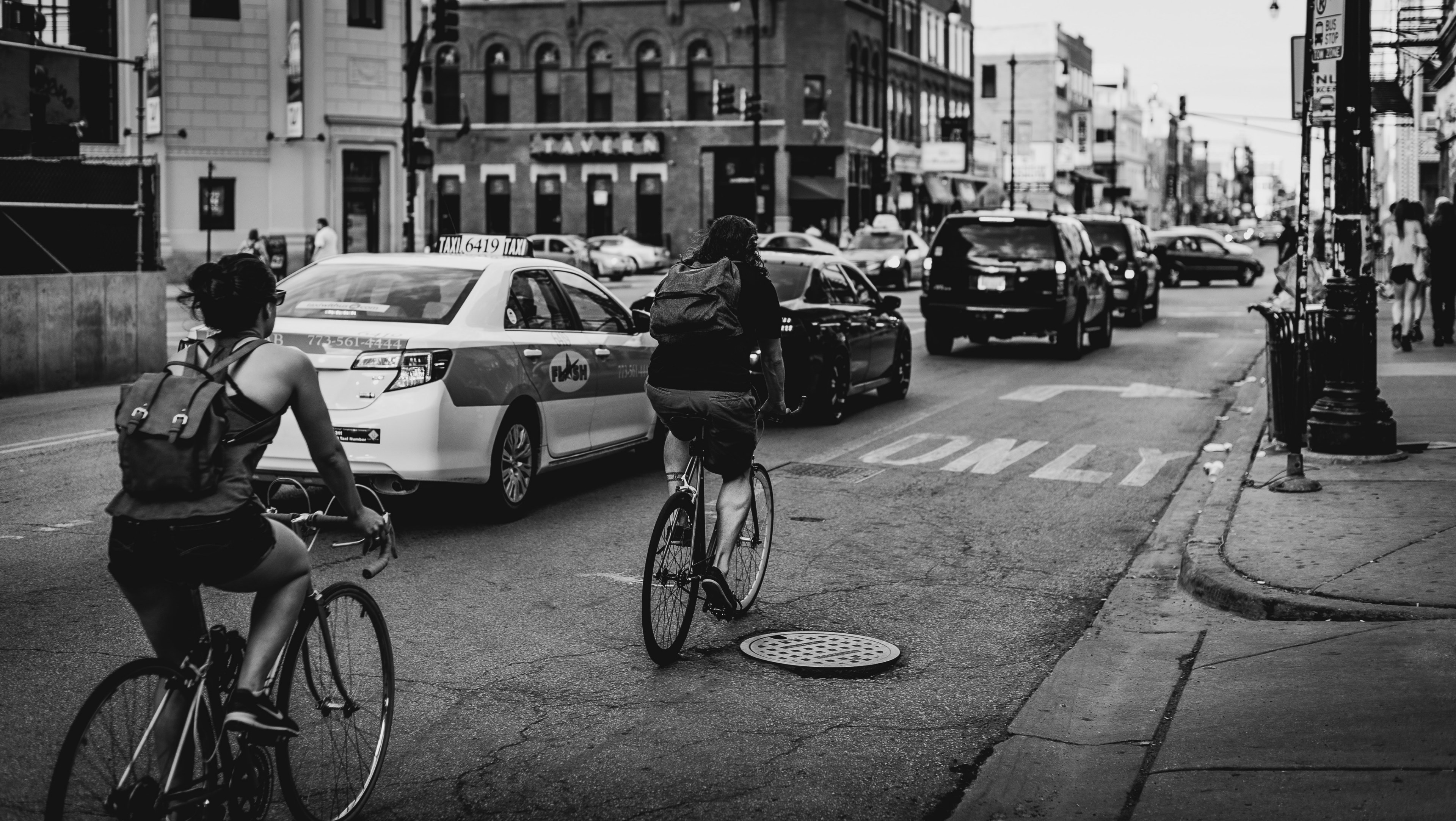 a black and white shot of two cyclists driving next to a column of cars in chicago, chicago cyclists in black and white 4k, HD Wallpaper
