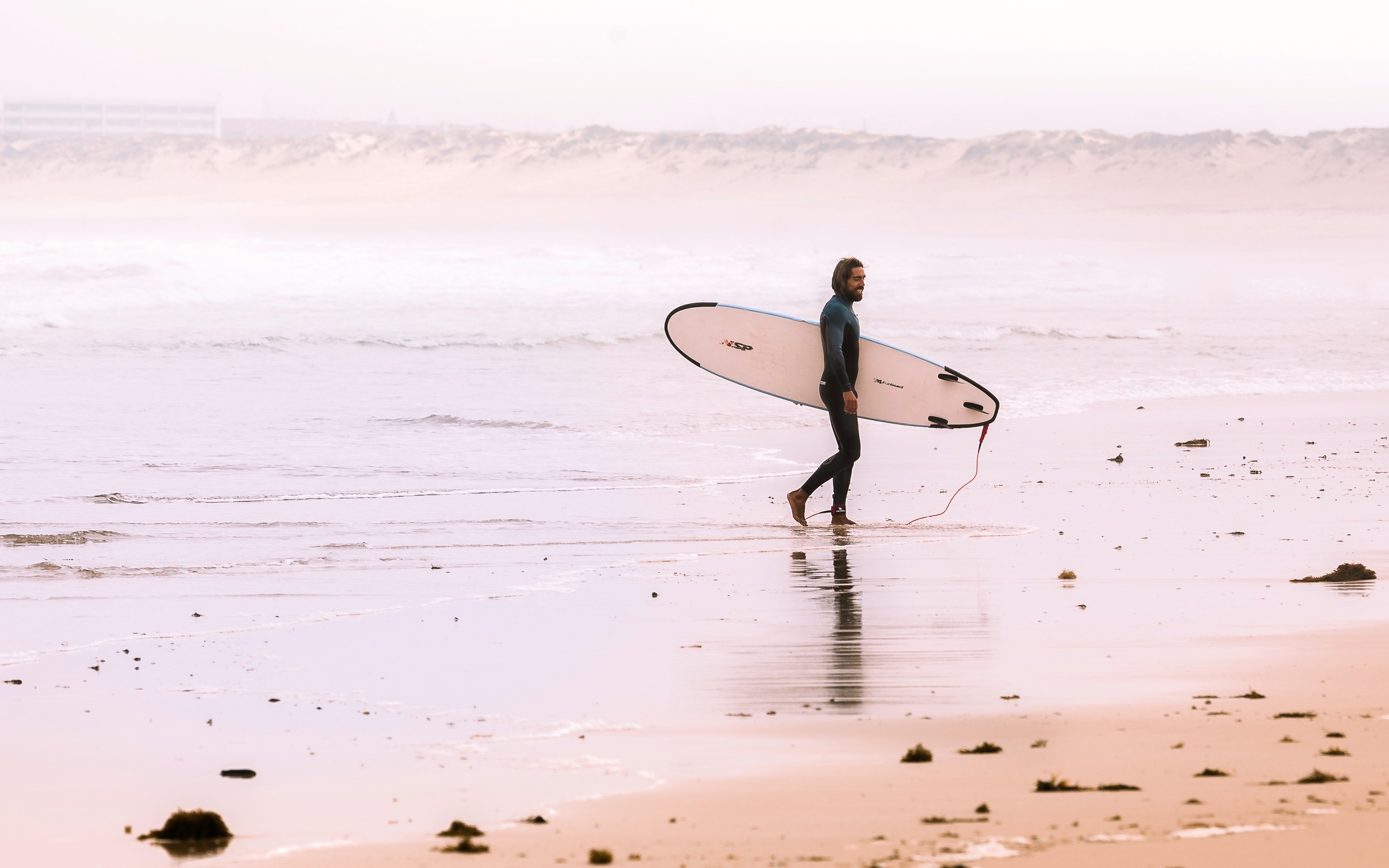 a male wearing a wetsuit holding a surfboard walking by the ocean in praia de peniche de cima, the end of a day of surfing 4k, HD Wallpaper