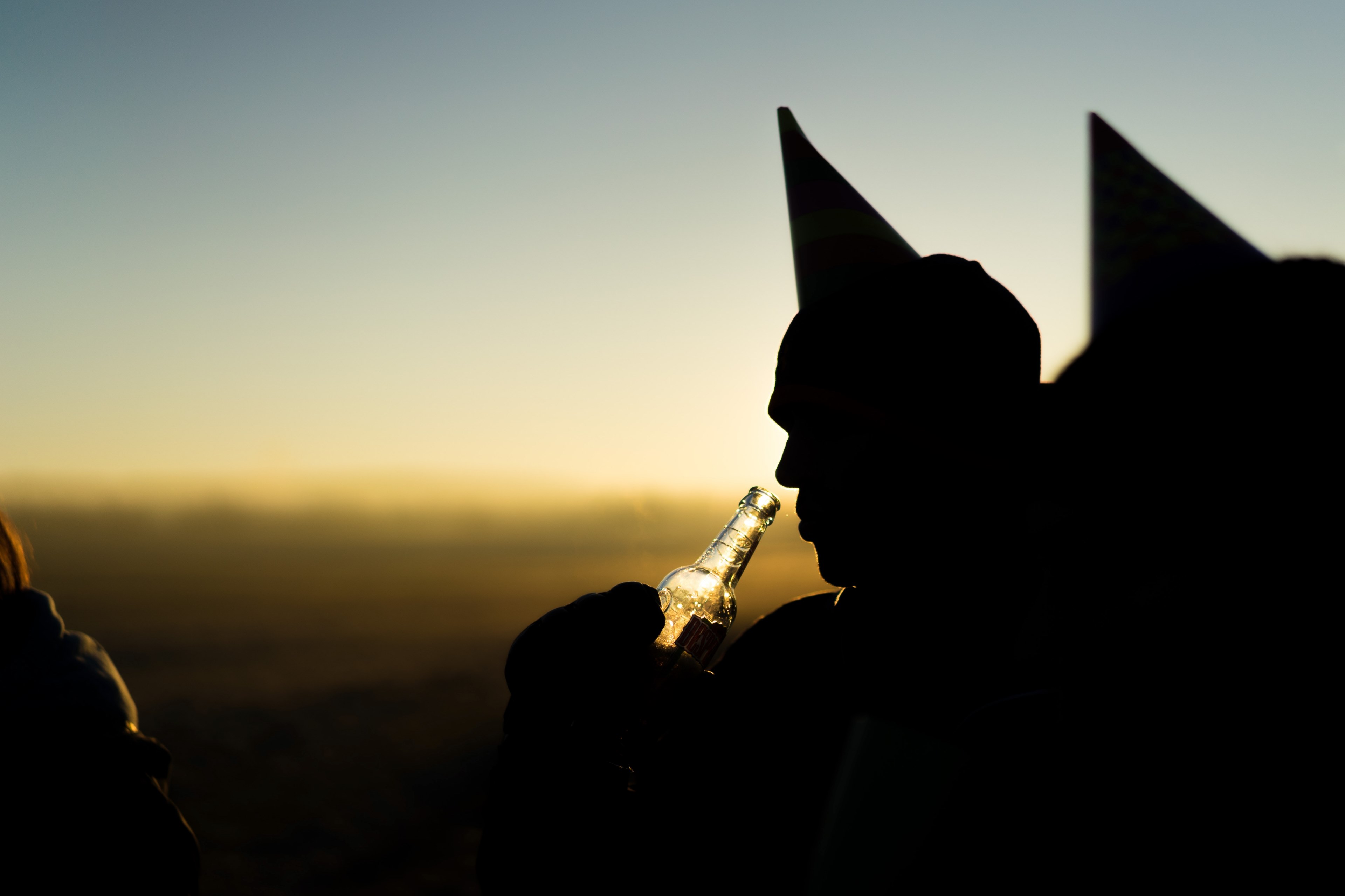 a silhouette of a man drinking from a beer bottle wearing a party hat, cheers 4k, HD Wallpaper